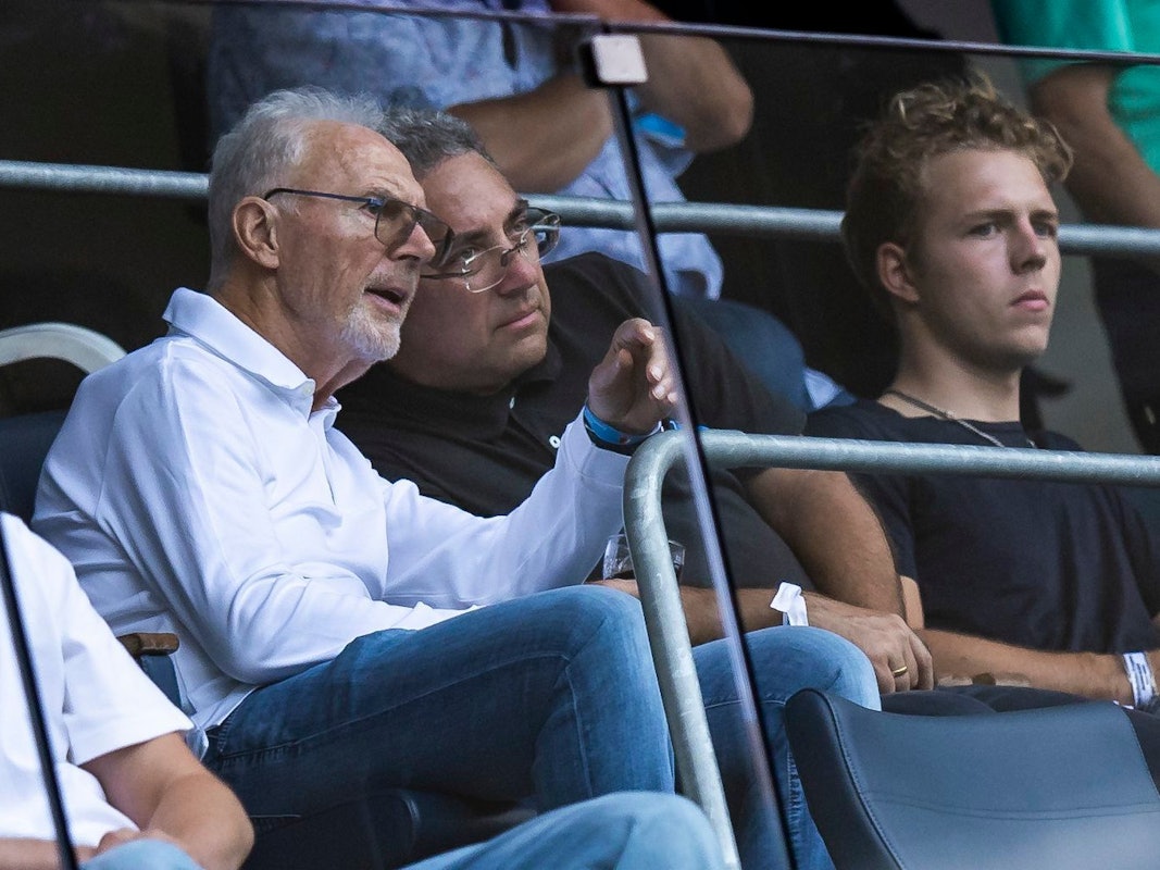 Franz Beckenbauer spricht beim Bundesliga-Spiel der TSG Hoffenheim auf der Tribüne mit seinem Nebenmann