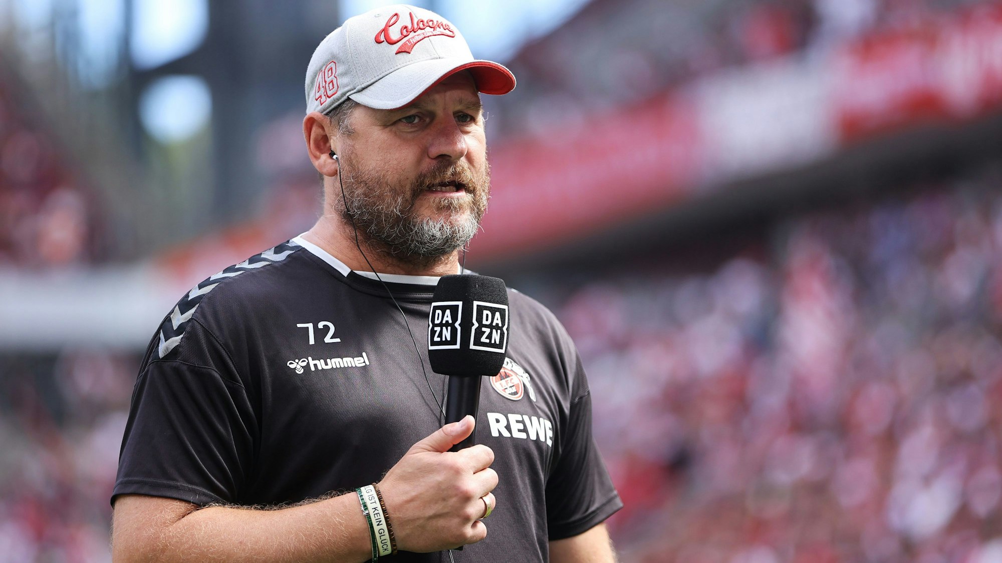 Steffen Baumgart steht am 28. August 2022 mit DAZN-Mikrofon im Stadion.