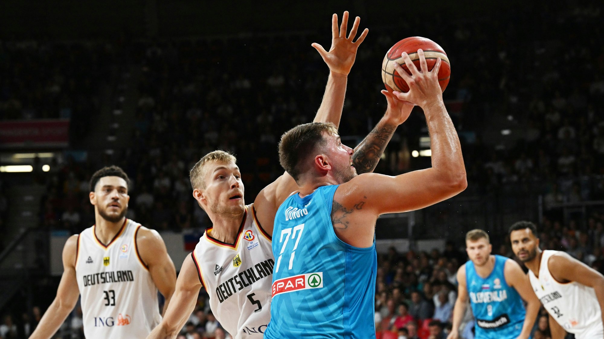 Deutschlands Gavin Schillingund Niels Giffey spielen gegen Sloweniens Luka Doncic den Ball.