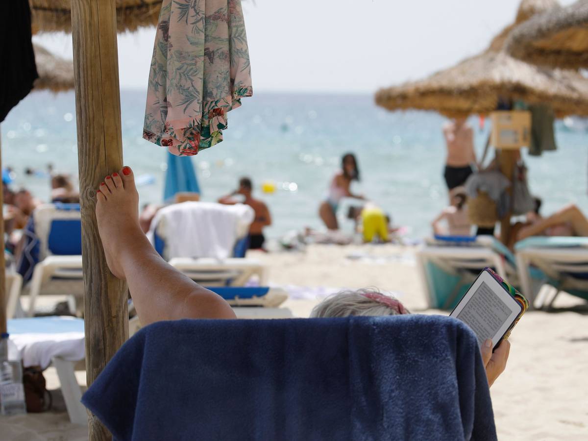 Eine Frau liegt auf einer Sonneliege am Strand von Mallorca