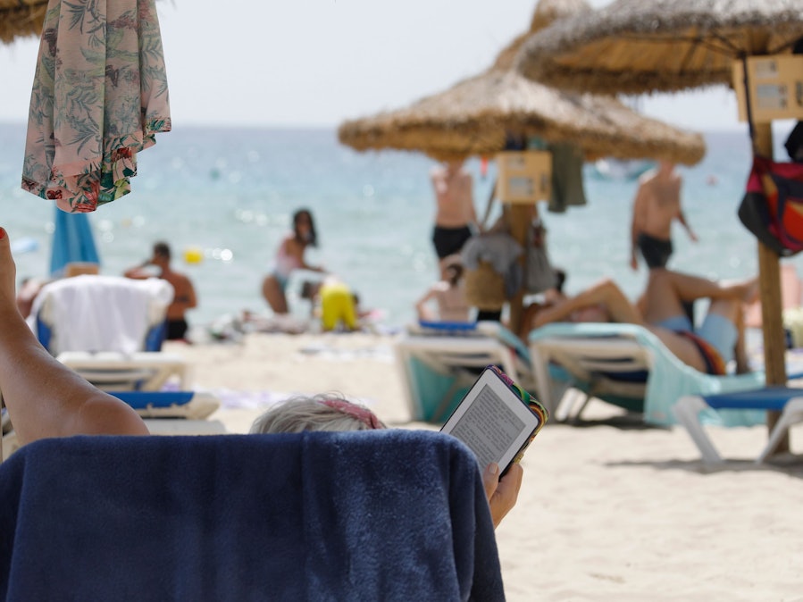 Eine Frau liegt auf einer Sonneliege am Strand von Mallorca