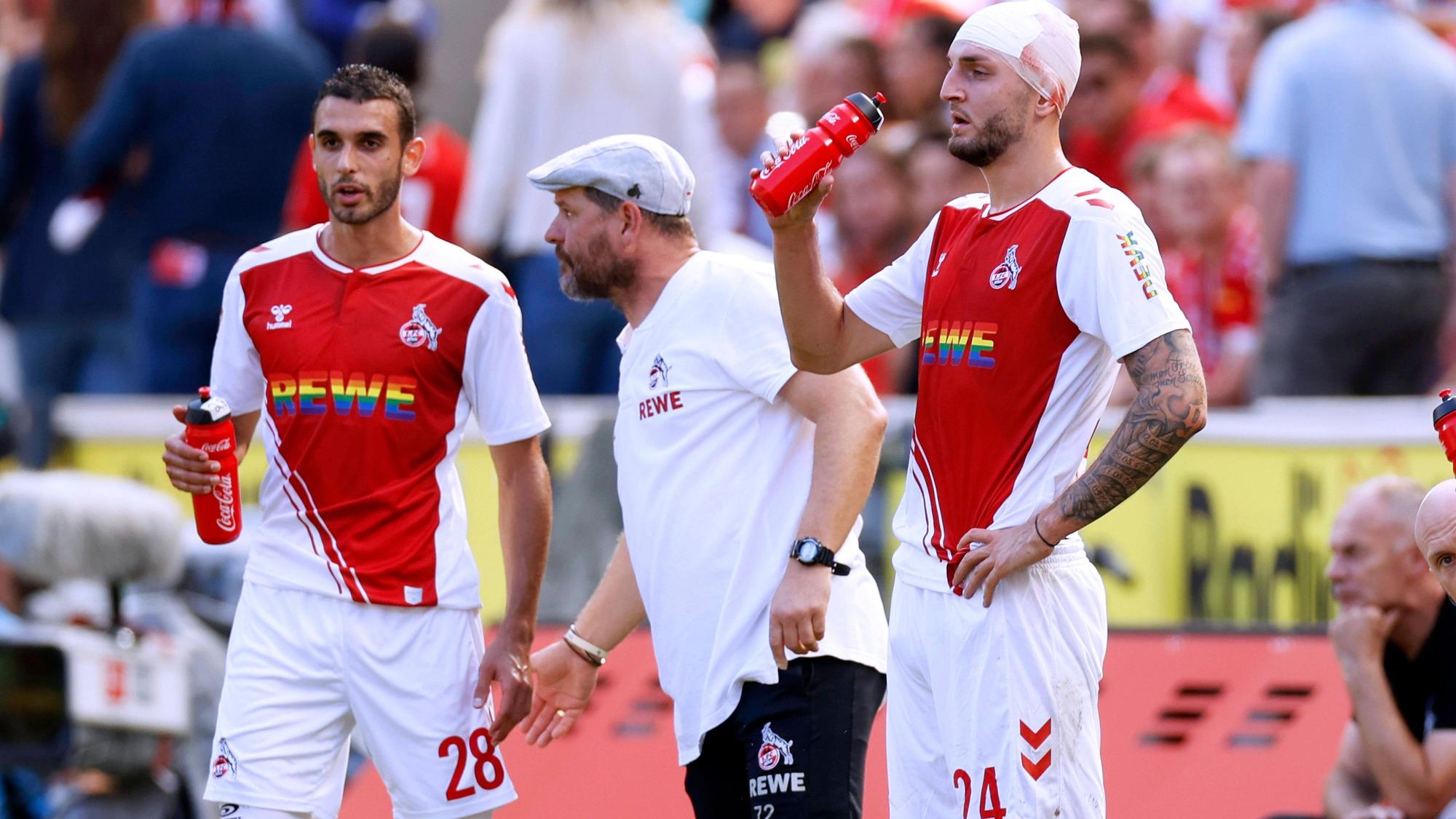Jeff Chabot (r.), und Ellyes Skhiri (l.) stehen am Spielfeldrand neben FC-Trainer Steffen Baumgart.