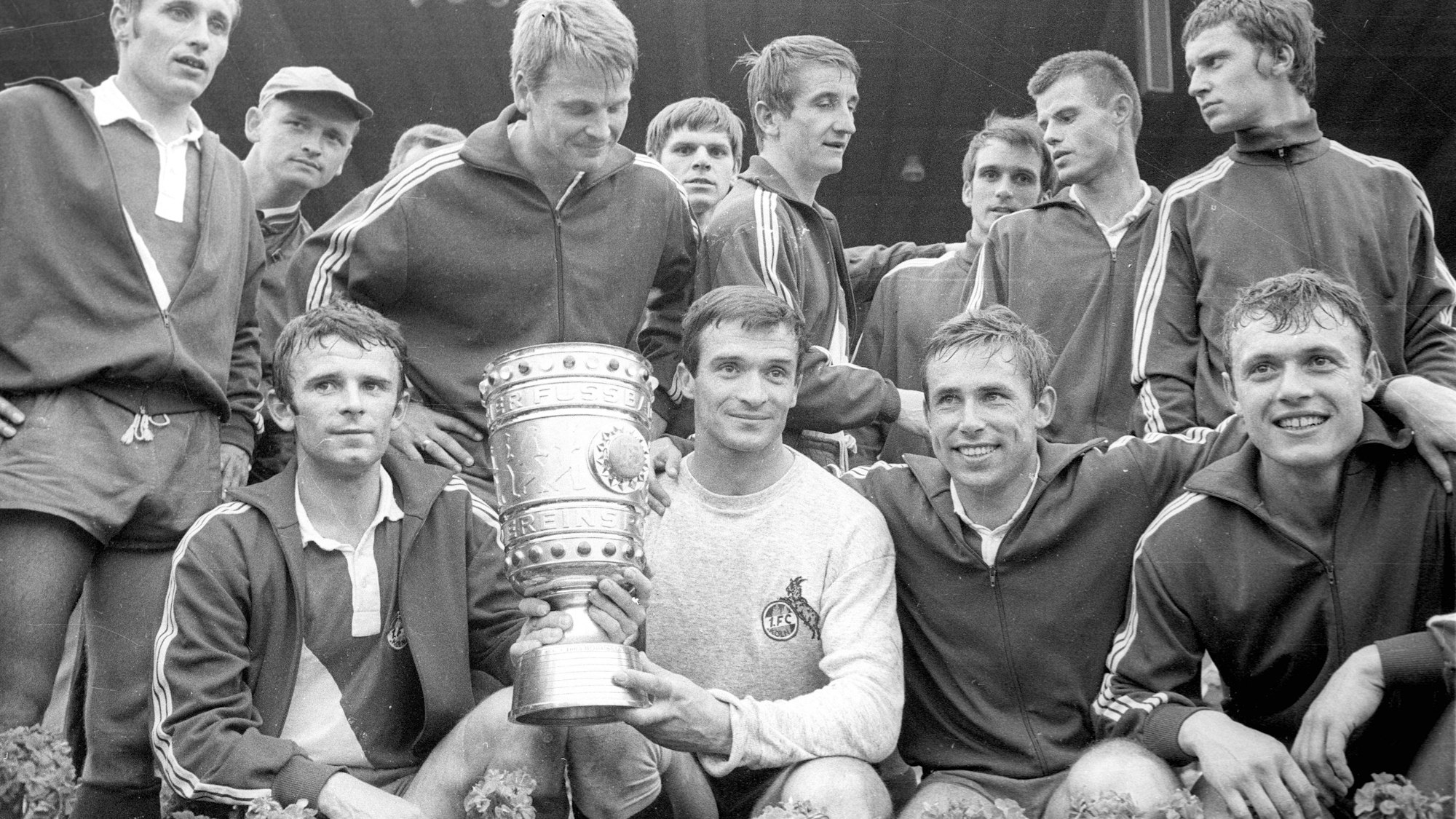 Milutin Soskic hält den DFB-Pokal und posiert mit seinen Teamkollegen des 1. F Köln