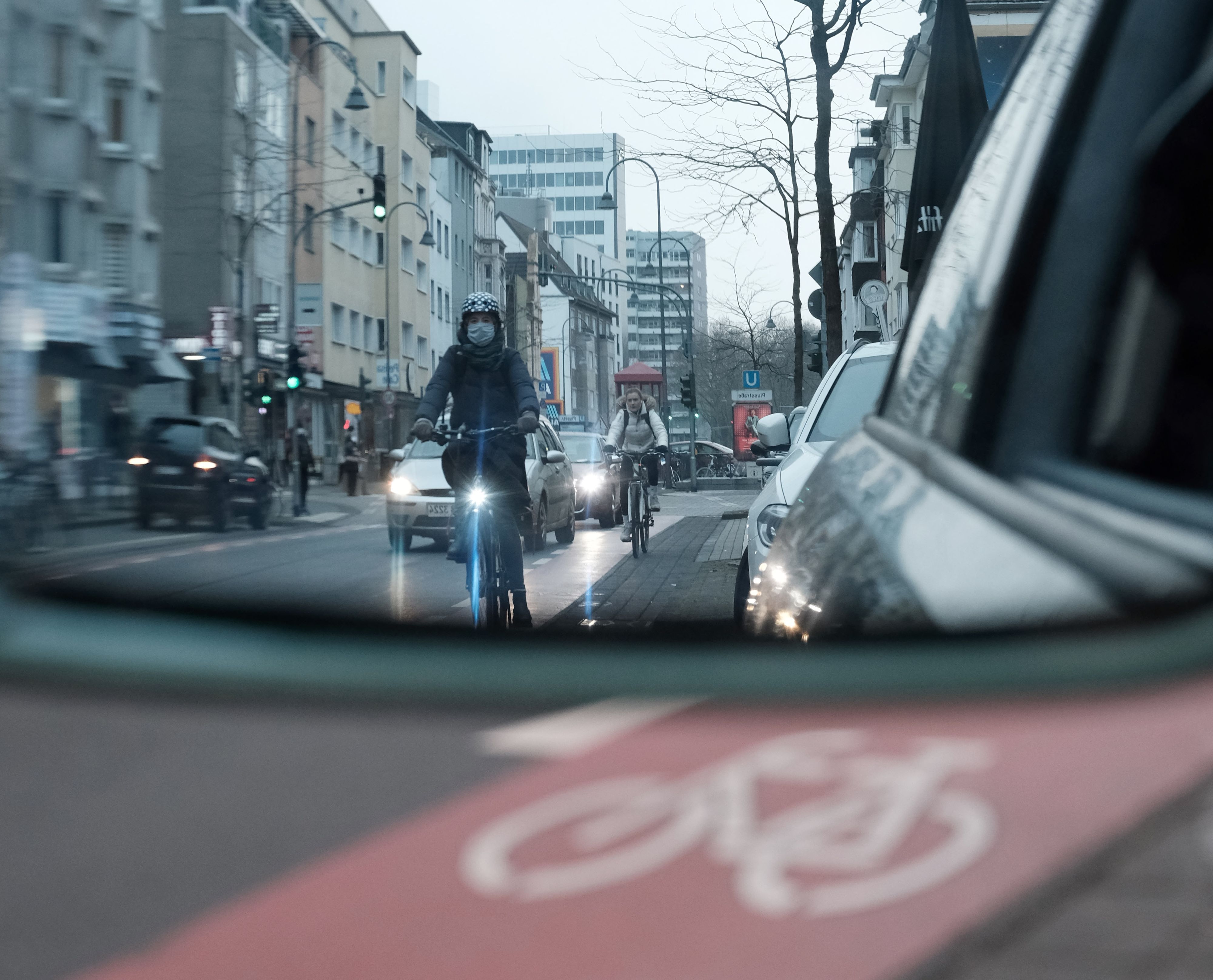 Radfahrer auf der Venloer Straße im Rückspiegel eines Autofahrers. Die Gefahr von Dooring-Unfällen ist in Städten sehr hoch.
