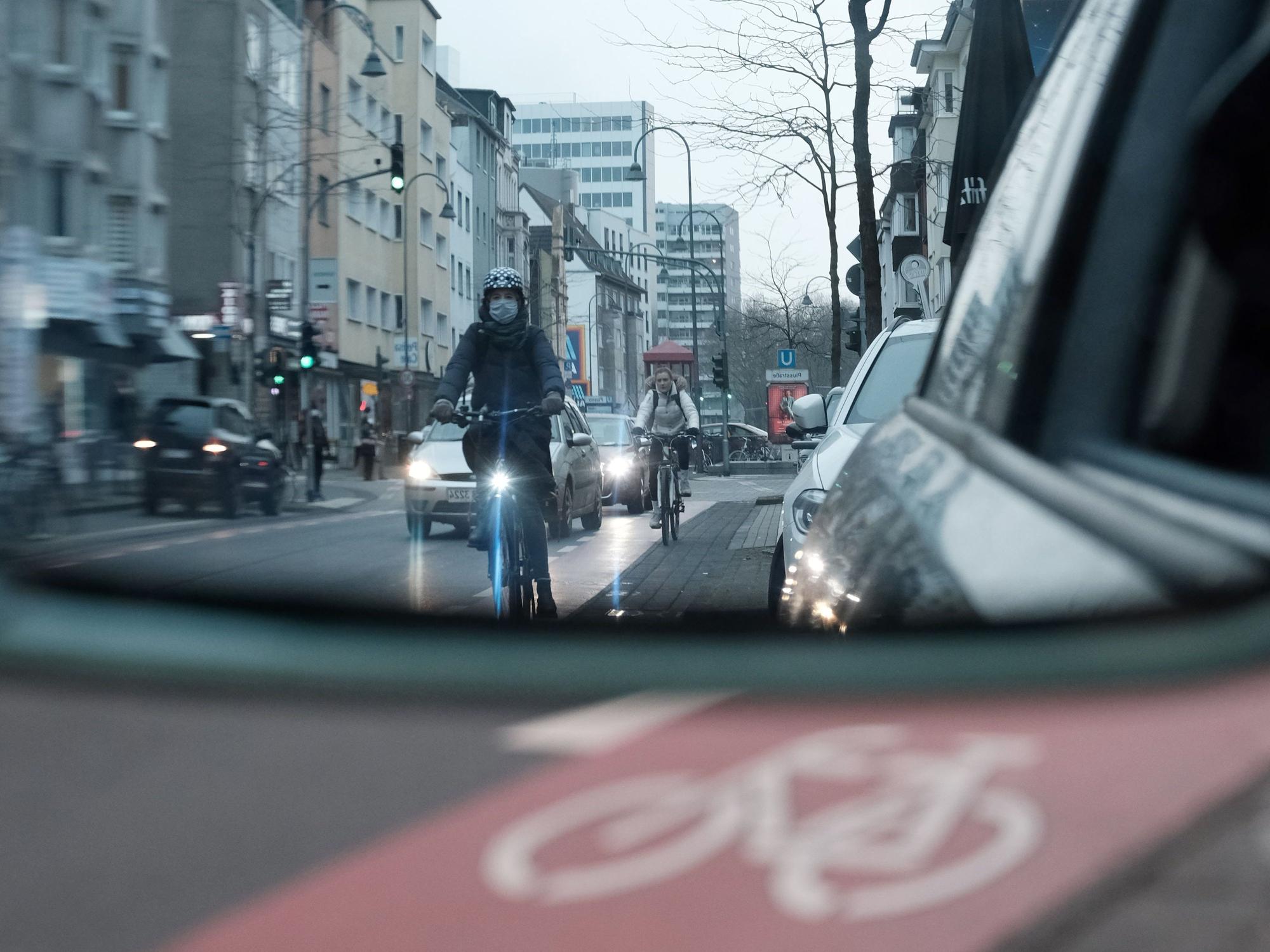 Radfahrer auf der Venloer Straße im Rückspiegel eines Autofahrers. Die Gefahr von Dooring-Unfällen ist in Städten sehr hoch.