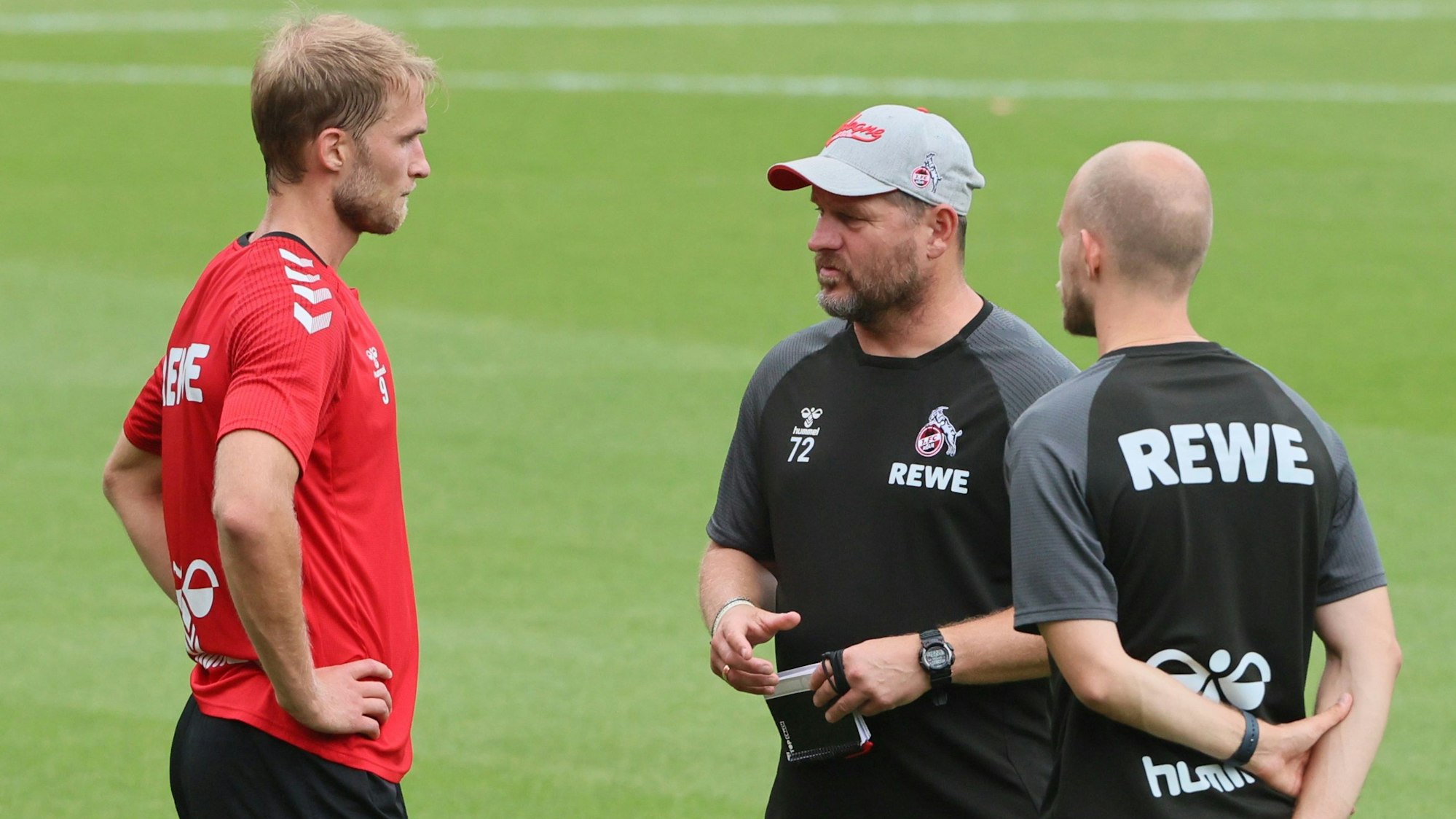 Sebastian Andersson steht mit Steffen Baumgart und Rene Wagner auf dem Trainingsplatz am Geißbockheim.