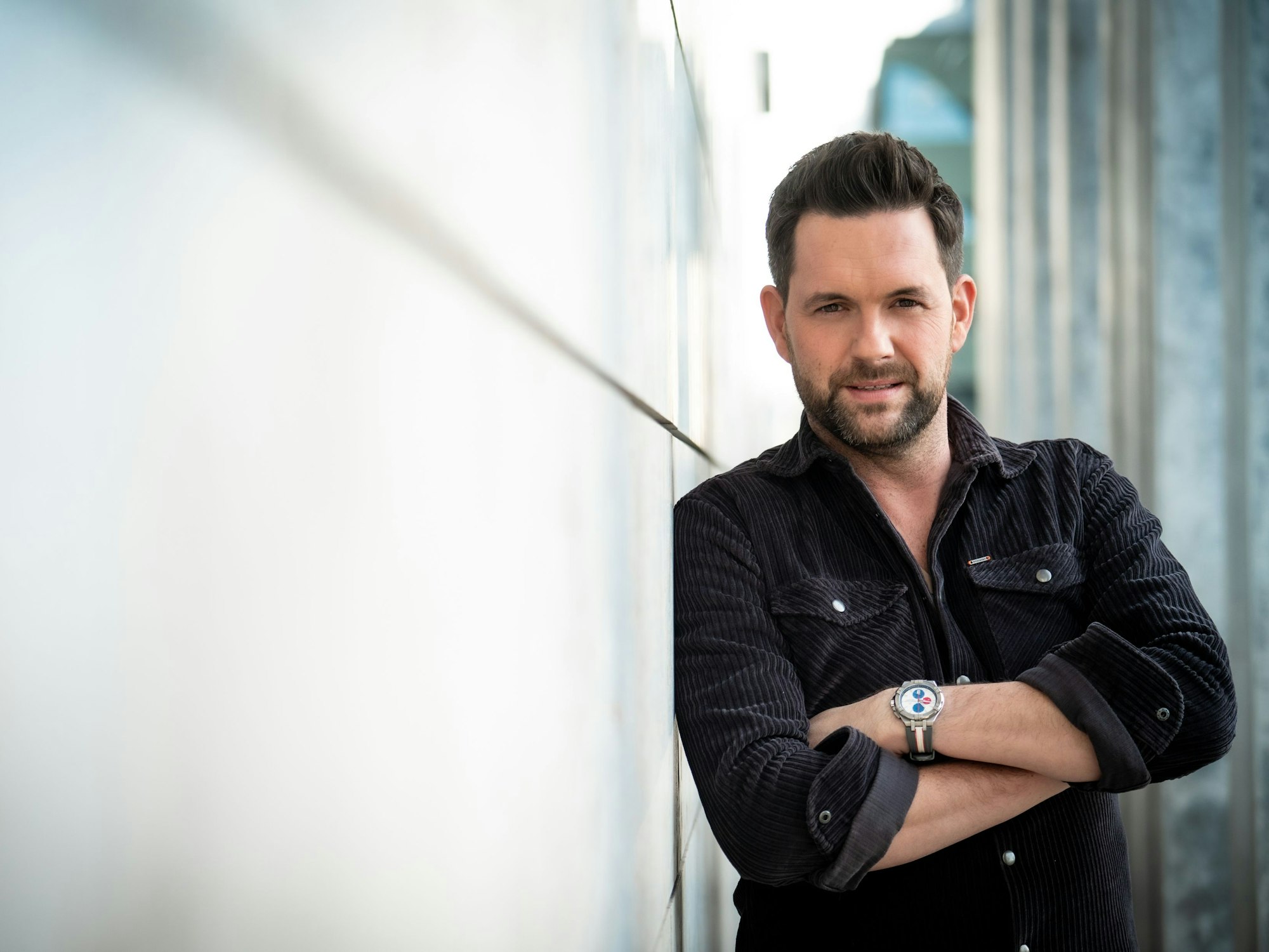Das Foto zeigt Moderator Matthias Killing vom Sat.1-„Frühstücksfernsehen“, der an einer Wand lehnt.