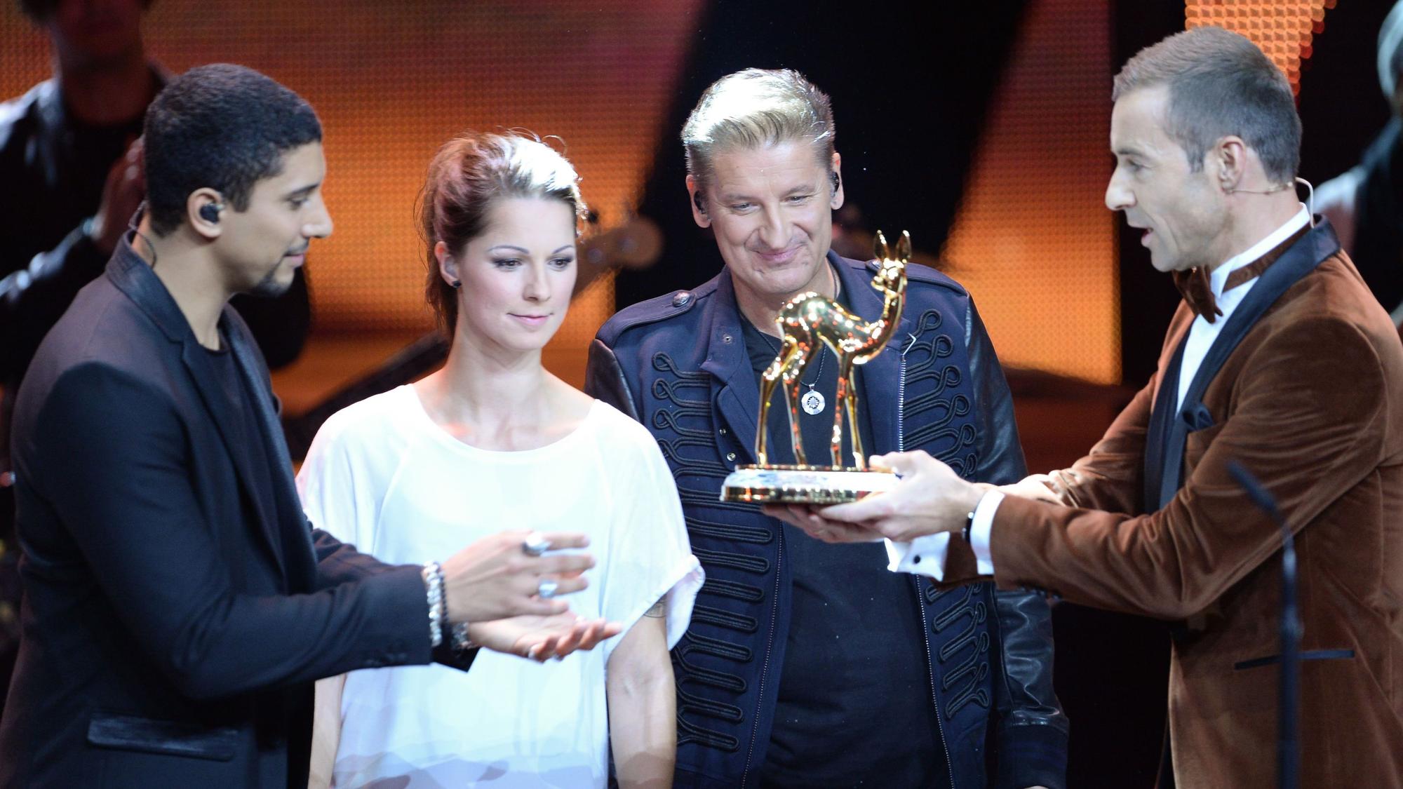 Moderator Kai Pflaume (r) zeichnet die Sänger Andreas Bourani (l-r), Christina Stürmer und Hartmut Engler stellvertretend für das Team von "Sing meinen Song" am 12.11.2015 in Berlin bei der 67. Bambi-Verleihung in der Kategorie "Musik national" aus.