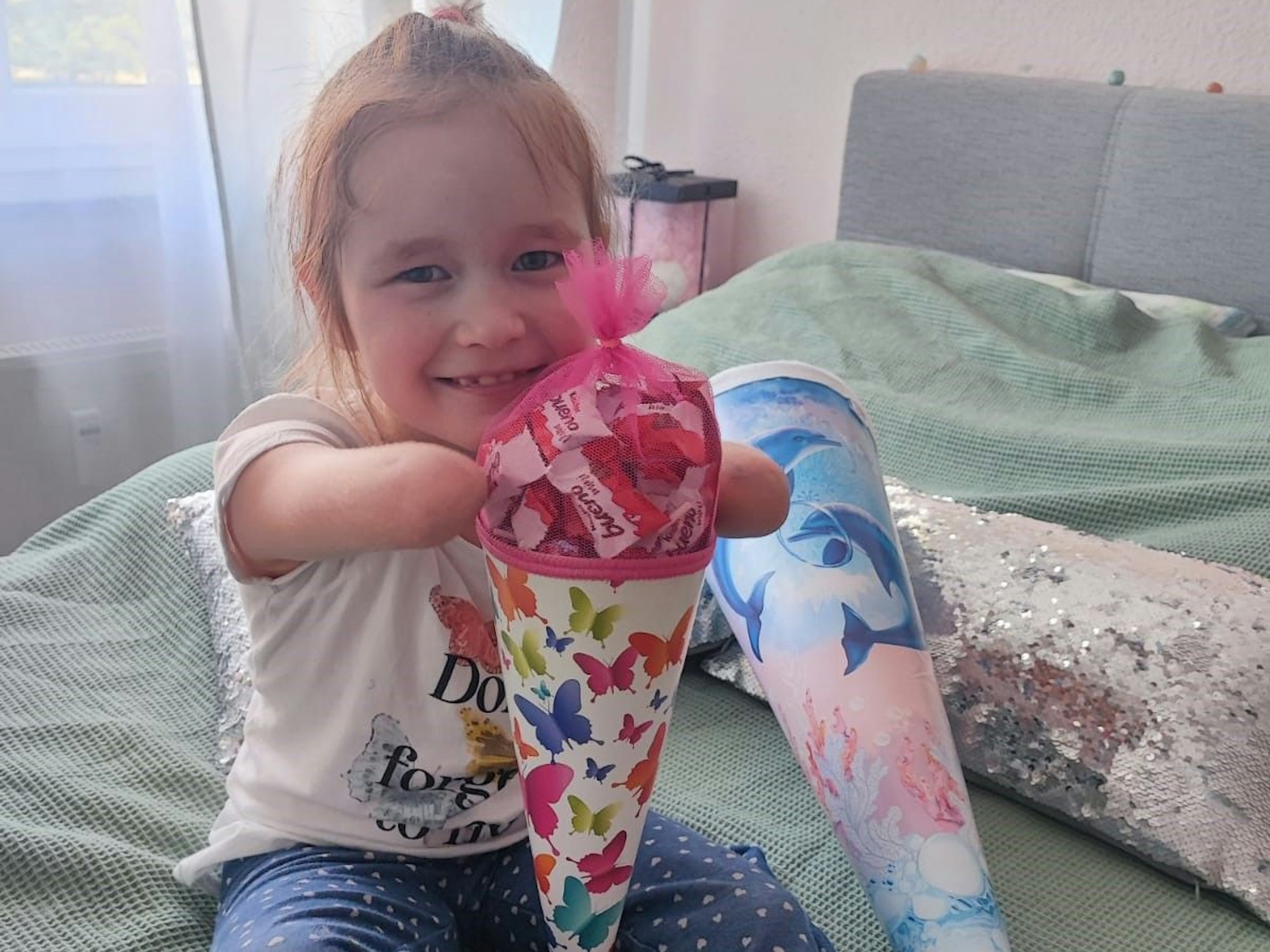 Ein Bild, das ans Herz geht: Milana hält glücklich und stolz ihre Schultüte zwischen den Ärmchen.