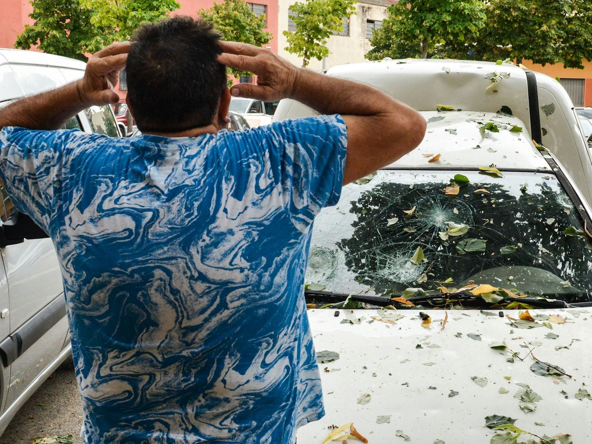 Ein Mann betrachtet sein Auto, das von dem Hagelsturm beschädigt wurde, welcher am Dienstag (30. August) über Katalonien hereingebrochen ist.