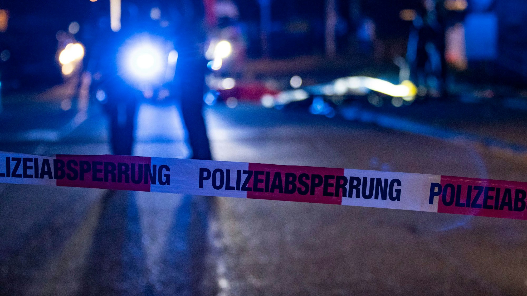 Absperrung der Polizei vor einem Tatort. Dahinter stehen Polizisten.