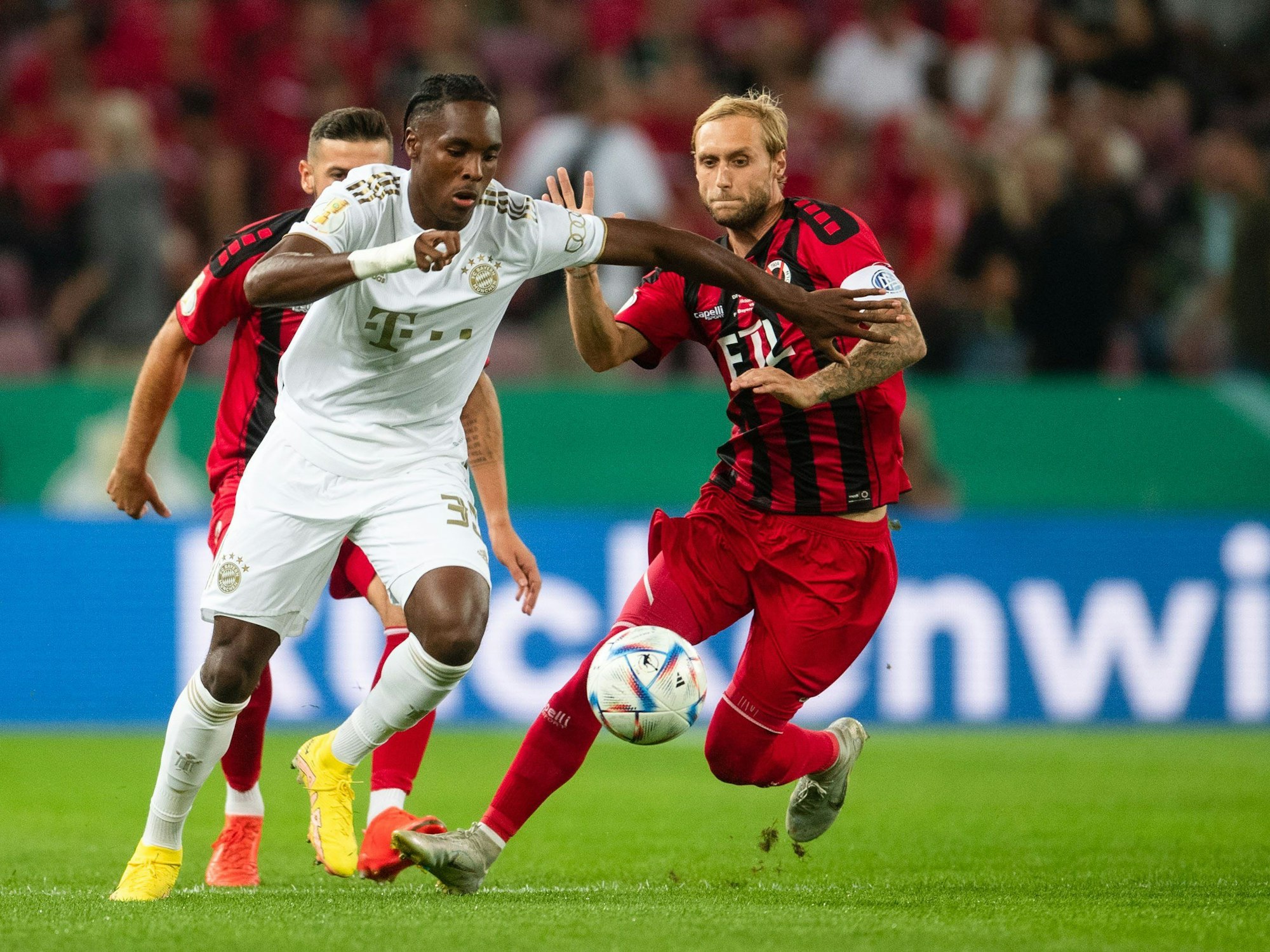 Kölns Marcel Risse (r) und Bayerns Mathys Tel kämpfen um den Ball.