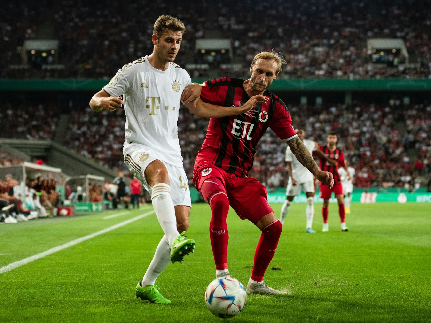 Bayerns Josip Stanisic (l) und Kölns Marcel Risse kämpfen um den Ball.