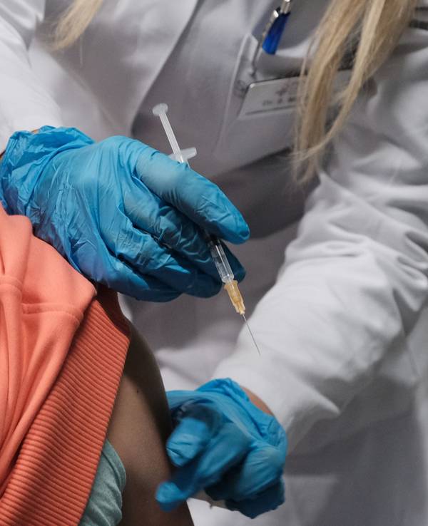 Eine Ärzten hält eine Spritze neben dem Arm einer Patientin.