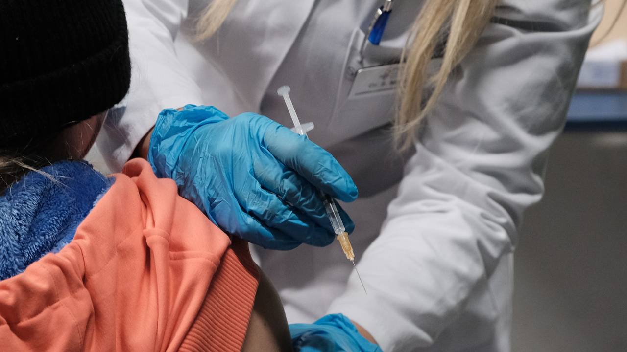 Eine Ärzten hält eine Spritze neben dem Arm einer Patientin.