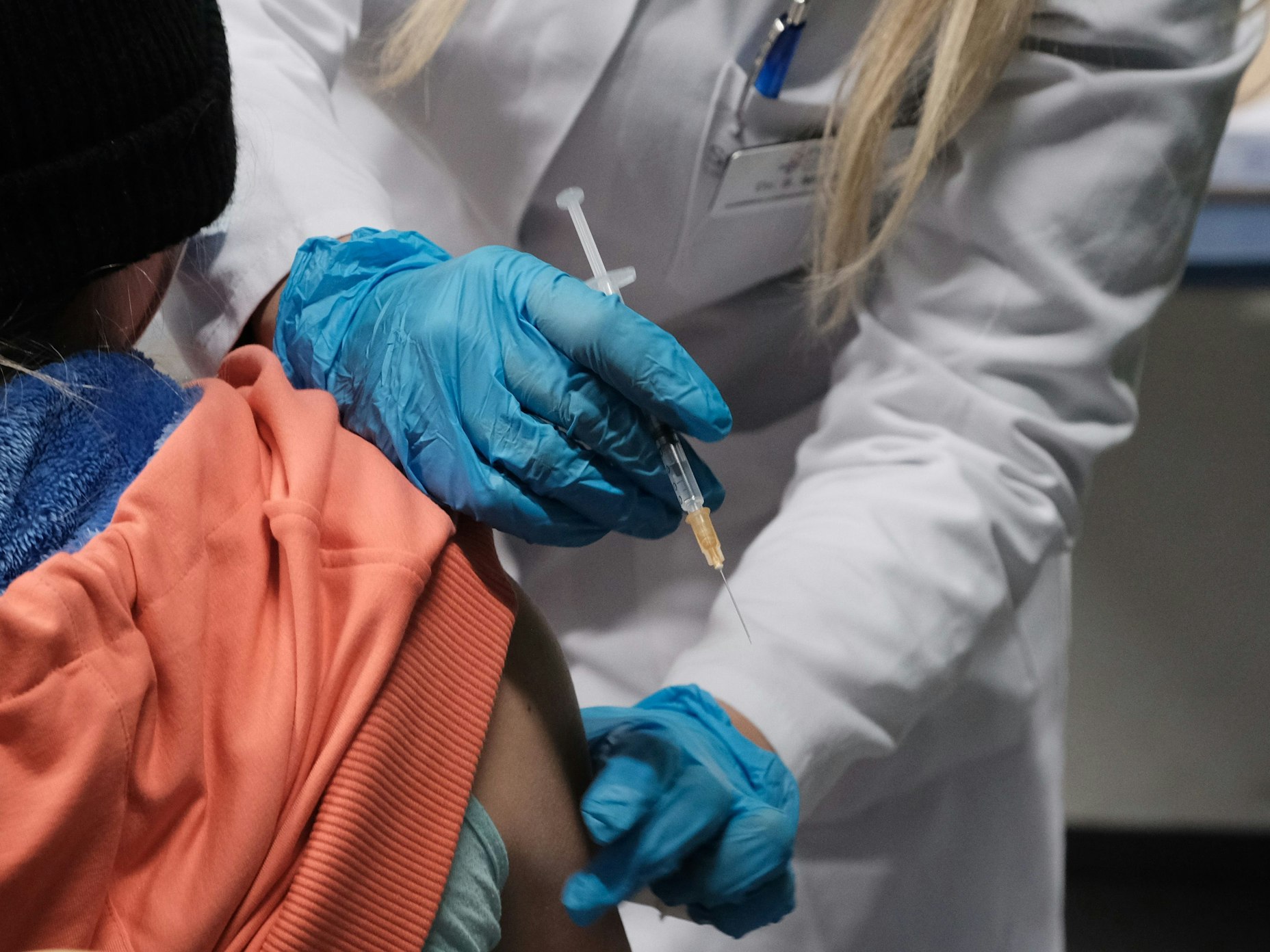 Eine Ärzten hält eine Spritze neben dem Arm einer Patientin.