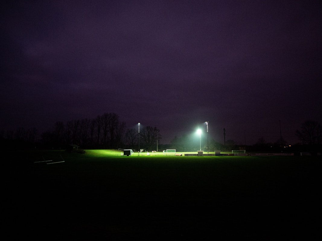 Eine Fußballmannschaft trainiert bei Flutlicht auf einem Sportplatz.