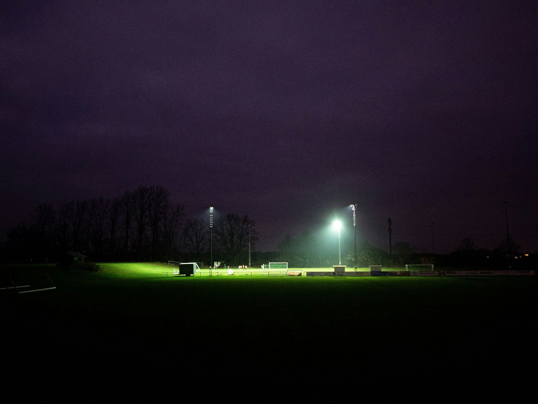 Eine Fußballmannschaft trainiert bei Flutlicht auf einem Sportplatz.