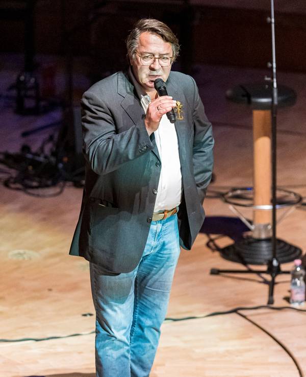 Hans Mörtter steht mit einem Mikrofon auf der Bühne der Kölner Philharmonie.