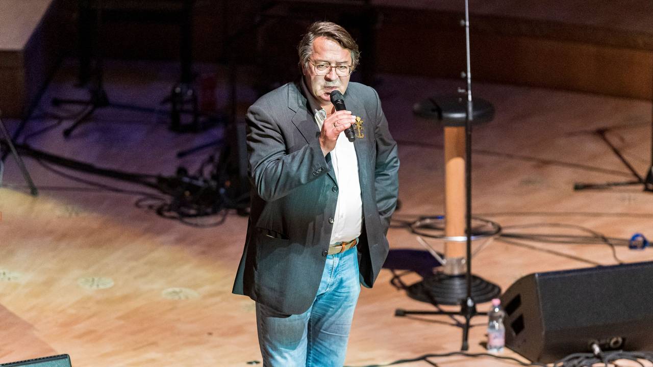 Hans Mörtter steht mit einem Mikrofon auf der Bühne der Kölner Philharmonie.