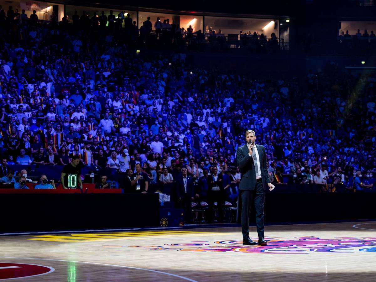 Dirk Nowitzki steht in der abgedunkelten Lanxess-Arena in Köln und hält mit Mikrofon eine Rede.