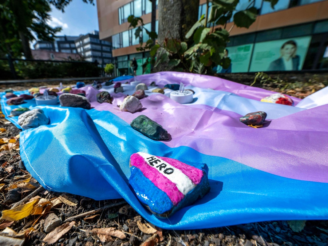 Menschen haben auf dem Hafenplatz eine Fahne ausgelegt, die mit bemalten Steinen beschwert ist.