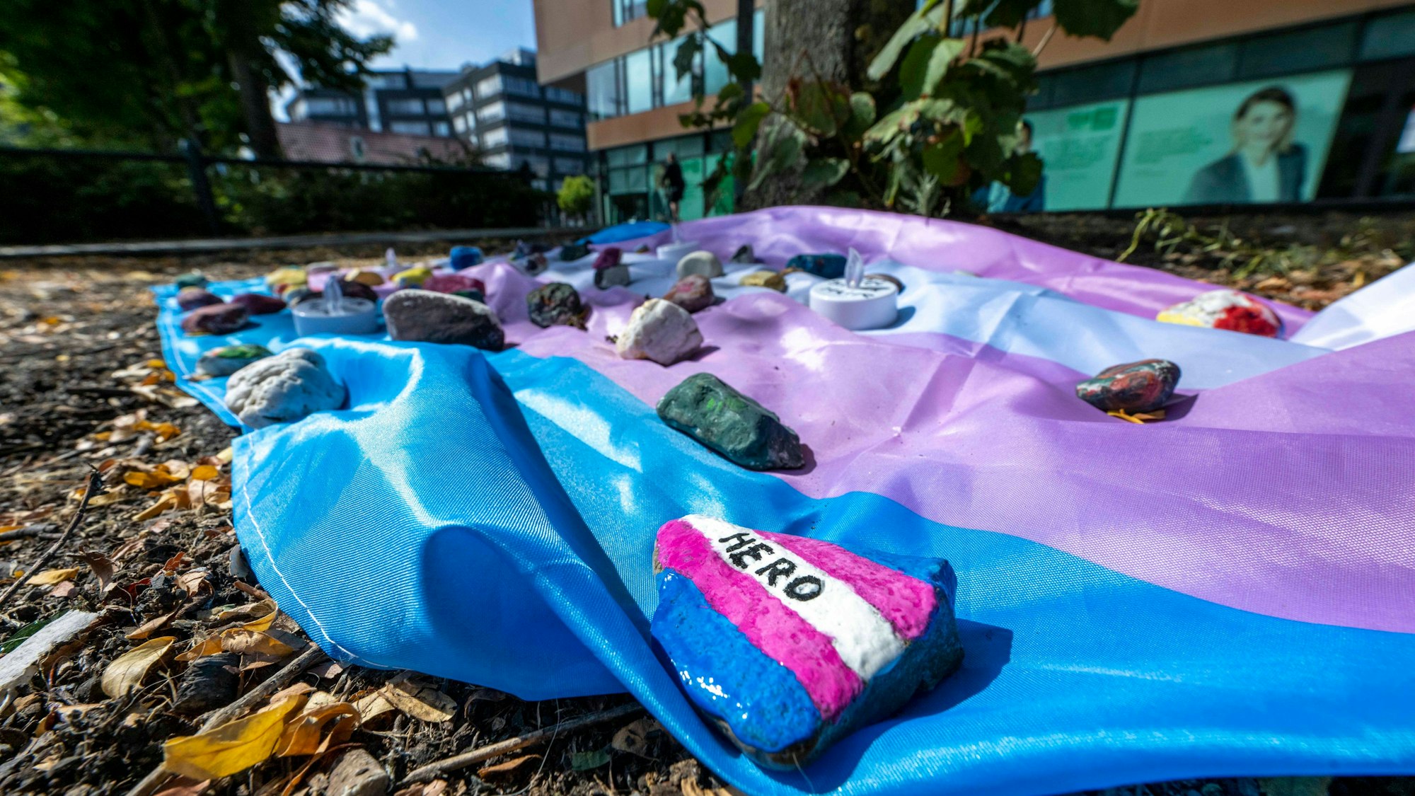 Menschen haben auf dem Hafenplatz eine Fahne ausgelegt, die mit bemalten Steinen beschwert ist.