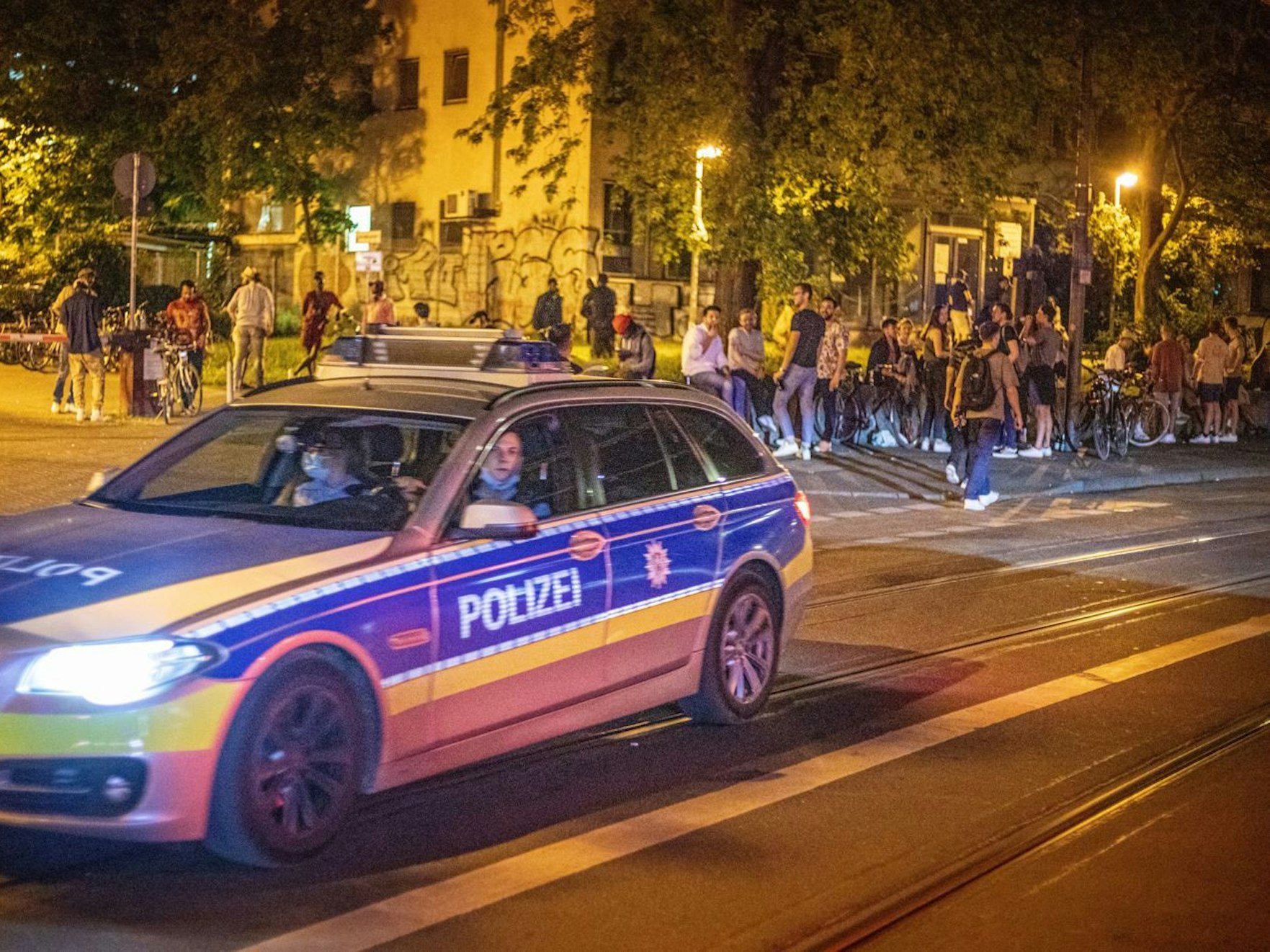 Polizei-Auto an der Zülpicher Straße in Köln, dahinter zahlreiche Menschen.