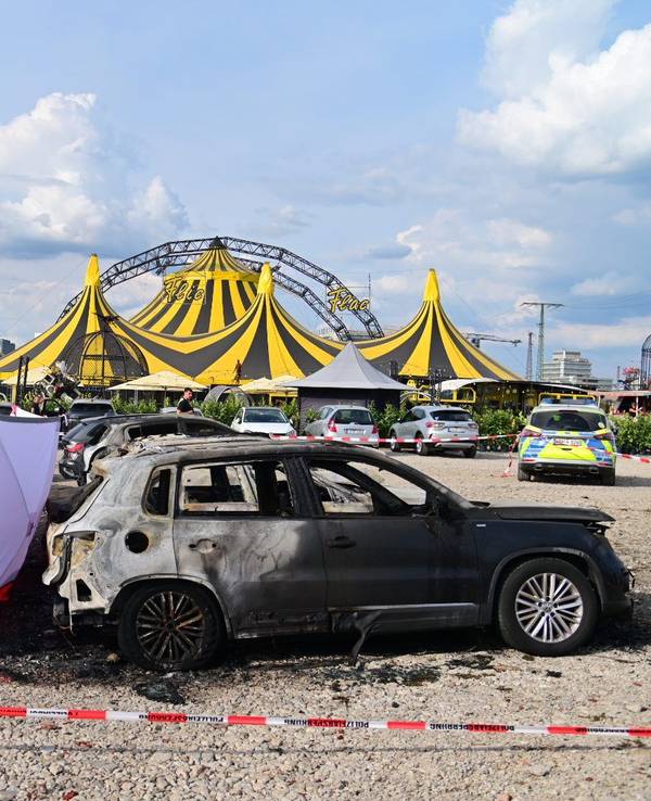 04.09.2022, Nordrhein-Westfalen, Duisburg: Ausgebrannte Fahrzeuge stehen vor dem Zelt des Zirkus FlicFlac, nachdem dort ein Kleinflugzeug abgestürzt war; die Unglücksstelle ist mit Sichtschutz umstellt. Beim dem Absturz des kleinmotorigen Flugzeugs in der Nähe der Autobahn A59 bei Duisburg sind zwei Menschen ums Leben gekommen. Foto: Christoph Reichwein/dpa +++ dpa-Bildfunk +++