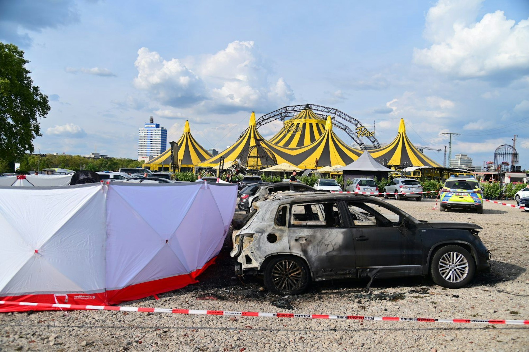 04.09.2022, Nordrhein-Westfalen, Duisburg: Ausgebrannte Fahrzeuge stehen vor dem Zelt des Zirkus FlicFlac, nachdem dort ein Kleinflugzeug abgestürzt war; die Unglücksstelle ist mit Sichtschutz umstellt. Beim dem Absturz des kleinmotorigen Flugzeugs in der Nähe der Autobahn A59 bei Duisburg sind zwei Menschen ums Leben gekommen. Foto: Christoph Reichwein/dpa +++ dpa-Bildfunk +++