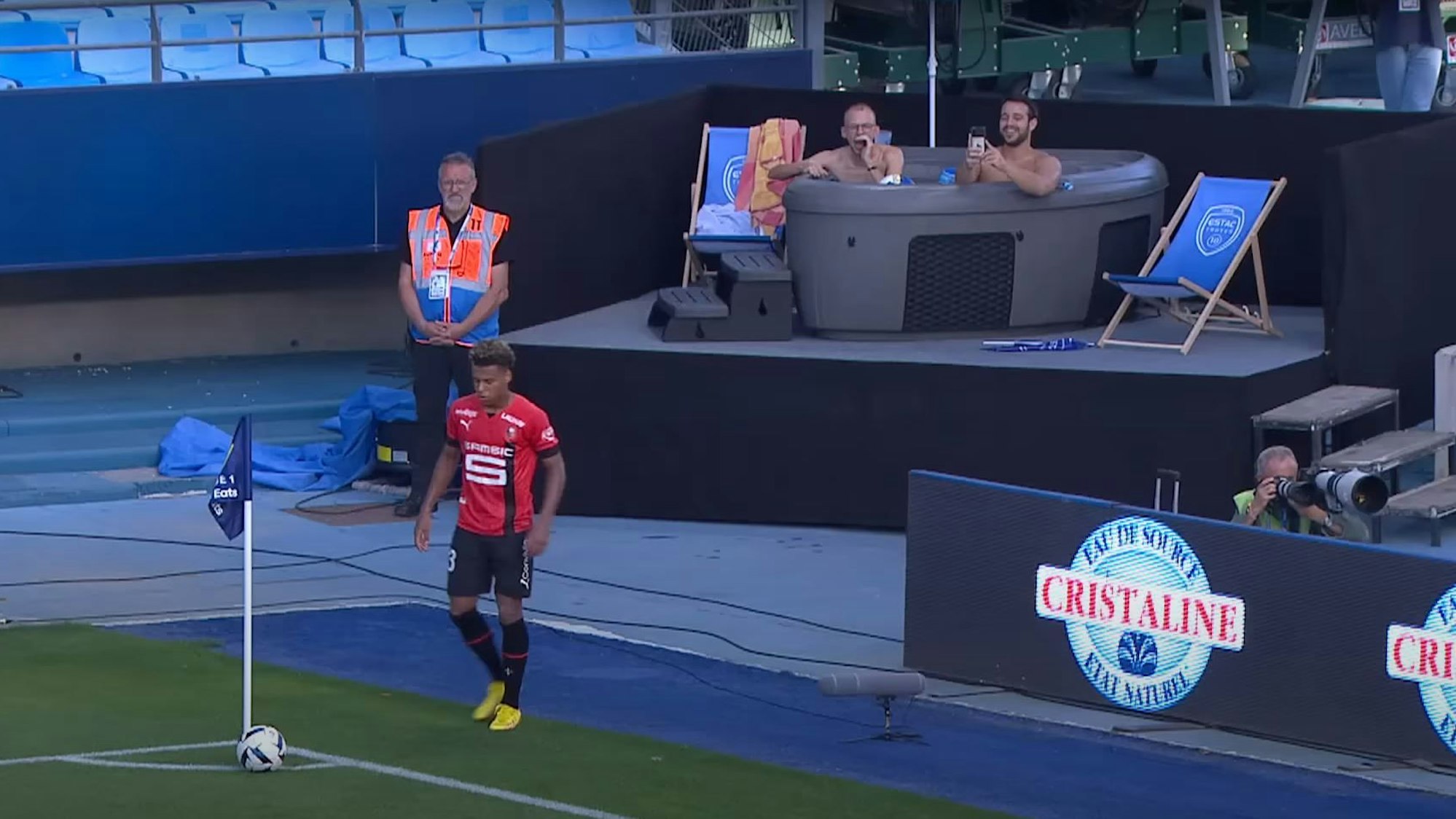 Zwei Fans von ESTAC Troyes sitzen beim Spiel gegen Stade Rennes in einem Jacuzzi am Spielfeldrand in einer Ecke des Stadions.