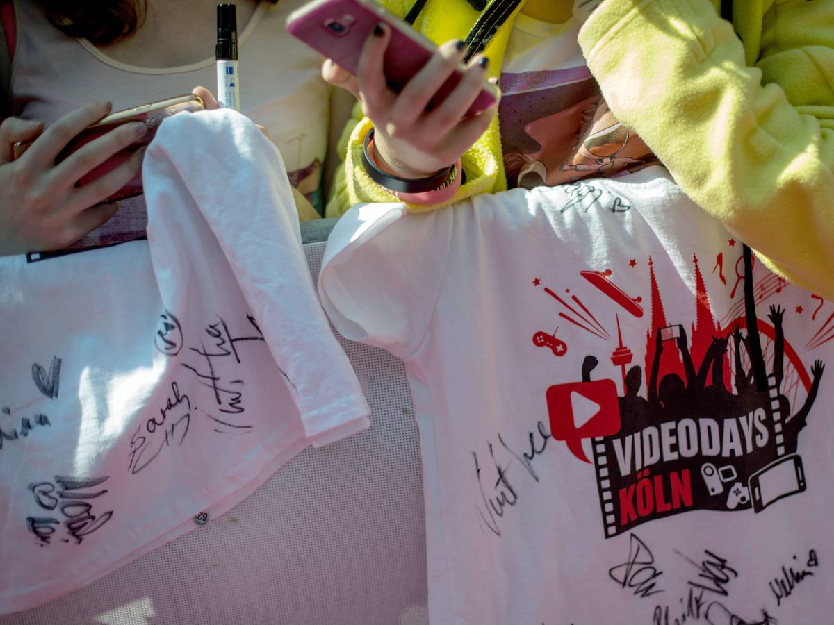 Fans stehen am 19.08.2016 in Köln beim YouTuber-Treffen "VideoDays" neben dem roten Teppich und halten ein T-Shirt mit Unterschrieften ihrer Stars.
