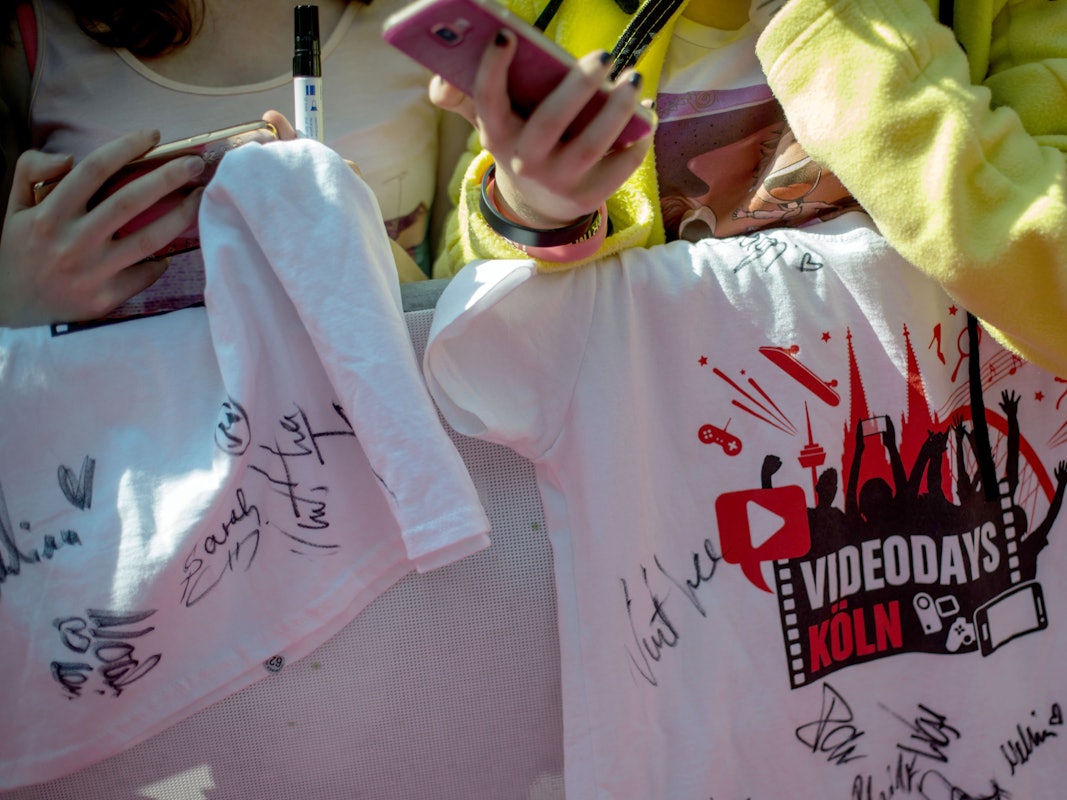 Fans stehen am 19.08.2016 in Köln beim YouTuber-Treffen "VideoDays" neben dem roten Teppich und halten ein T-Shirt mit Unterschrieften ihrer Stars.