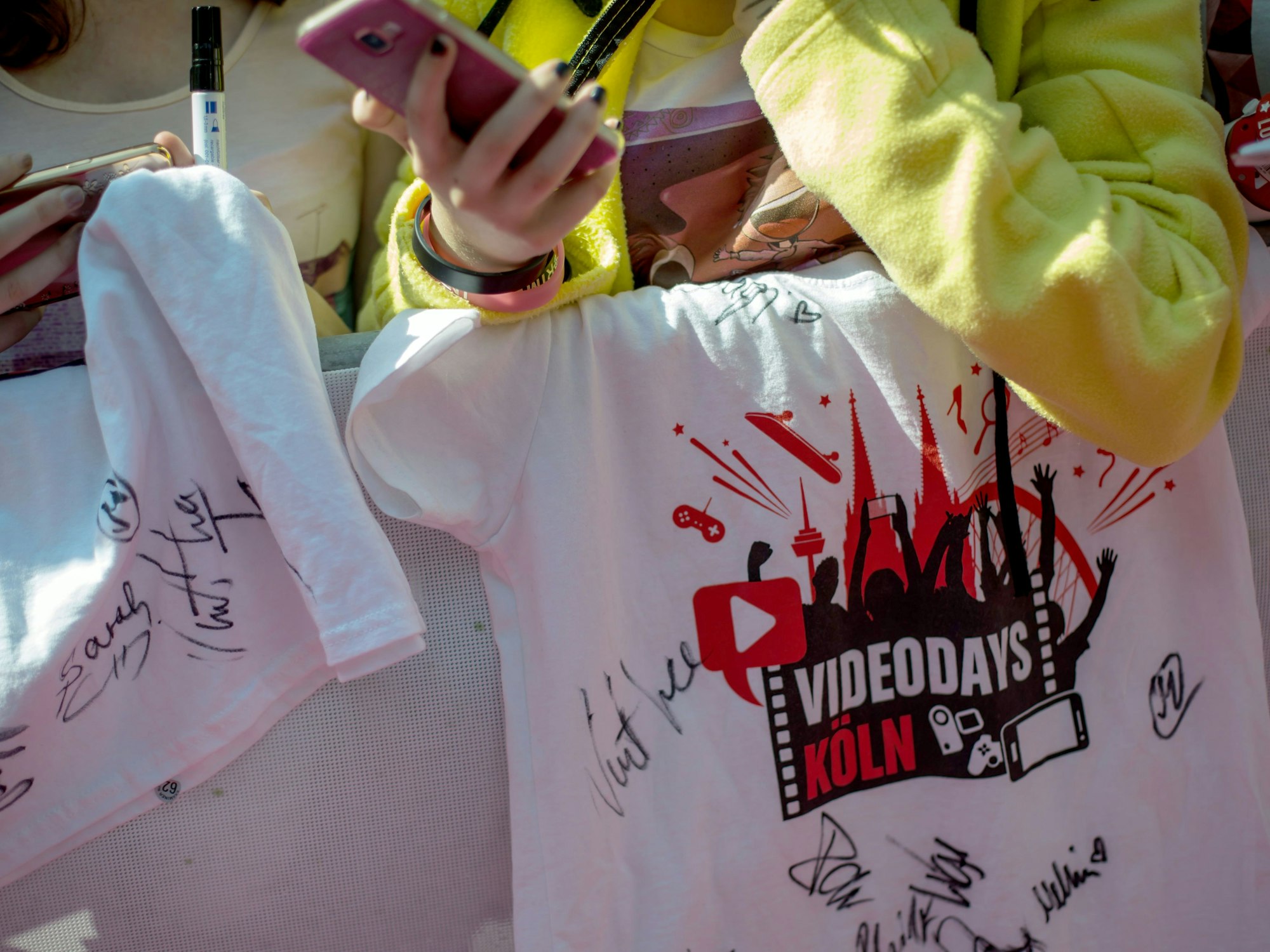 Fans stehen am 19.08.2016 in Köln beim YouTuber-Treffen "VideoDays" neben dem roten Teppich und halten ein T-Shirt mit Unterschrieften ihrer Stars.