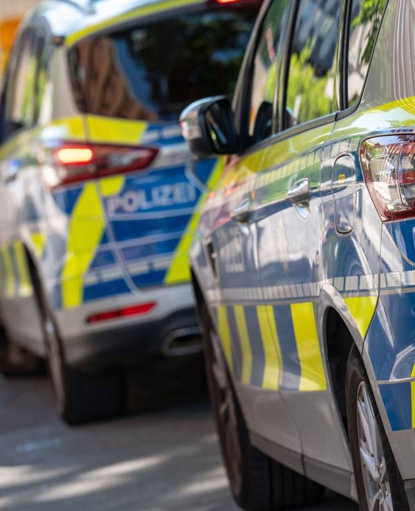 Zwei Polizeifahrzeuge stehen an der Straße