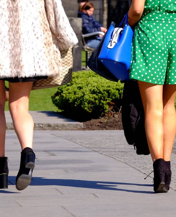 Zwei Frauen in kurzen Röcken gehen auf einem Weg.