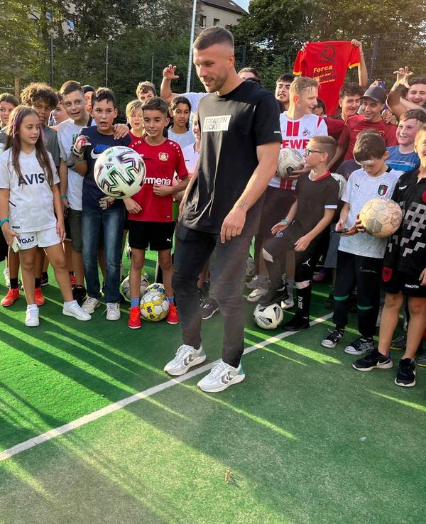 Lukas Podolski hält den Ball hoch.