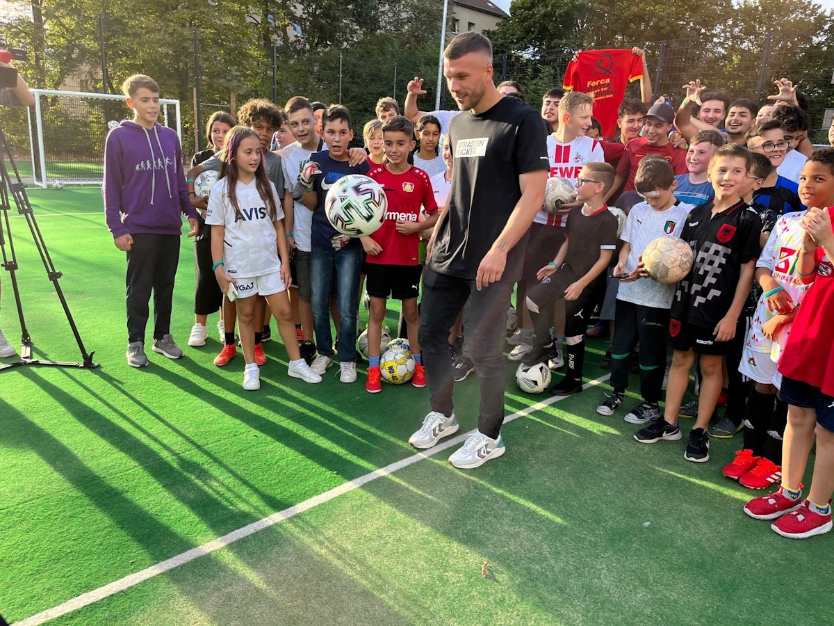 Lukas Podolski hält den Ball hoch.