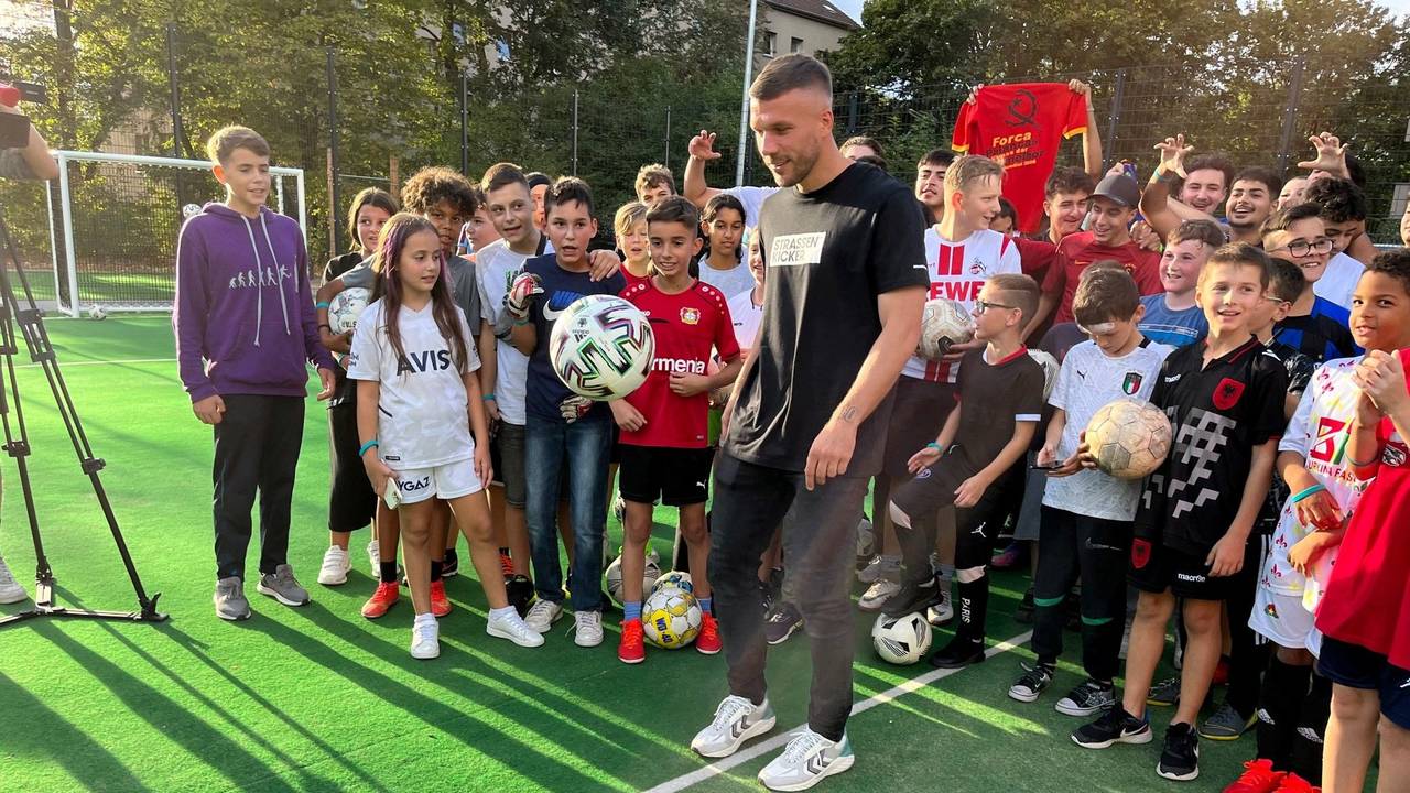 Lukas Podolski hält den Ball hoch.