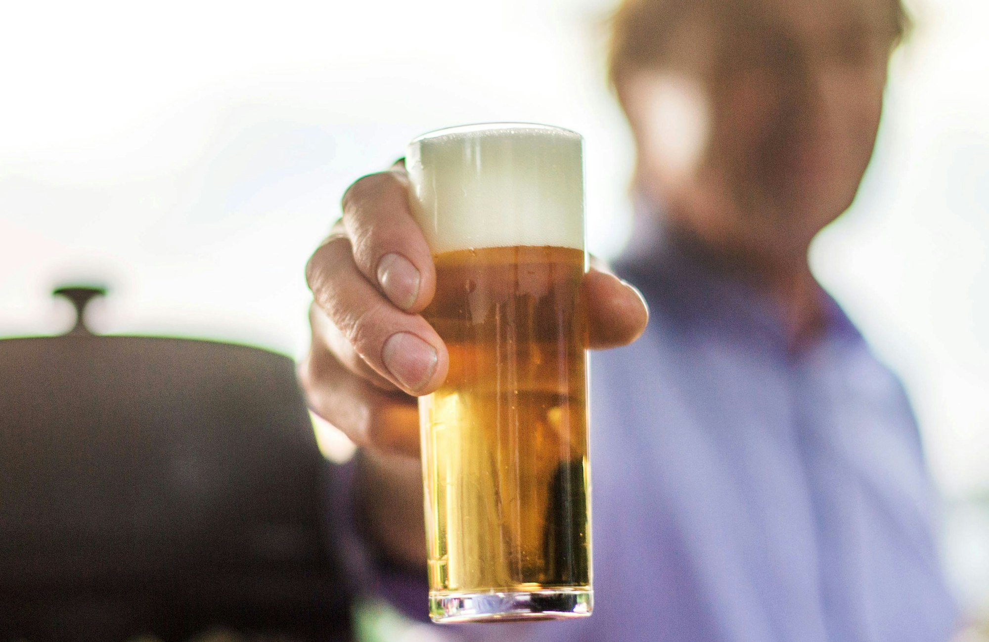 Ein Köbes hält ein Kölsch in die Kamera