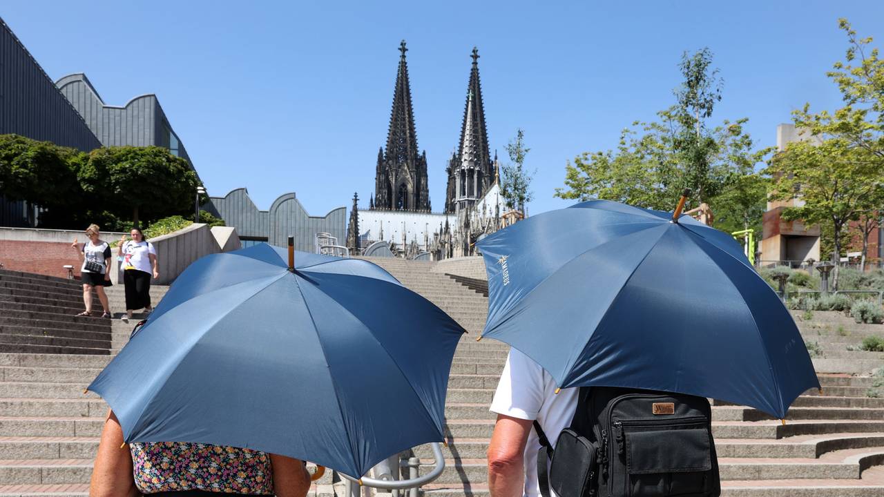 Zwei Erwachsene schützen sich mit Schirmen vor der Hitze.