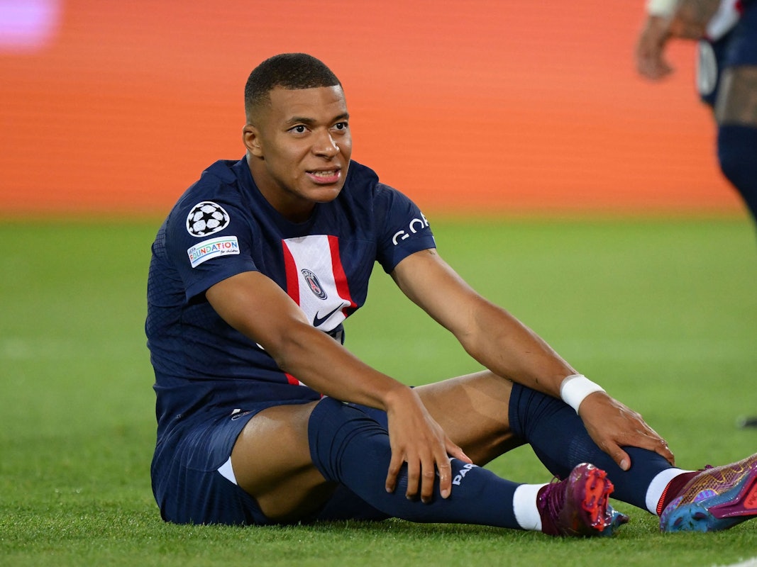 Kylian Mbappé sitzt bei einem Spiel von PSG auf dem Rasen.