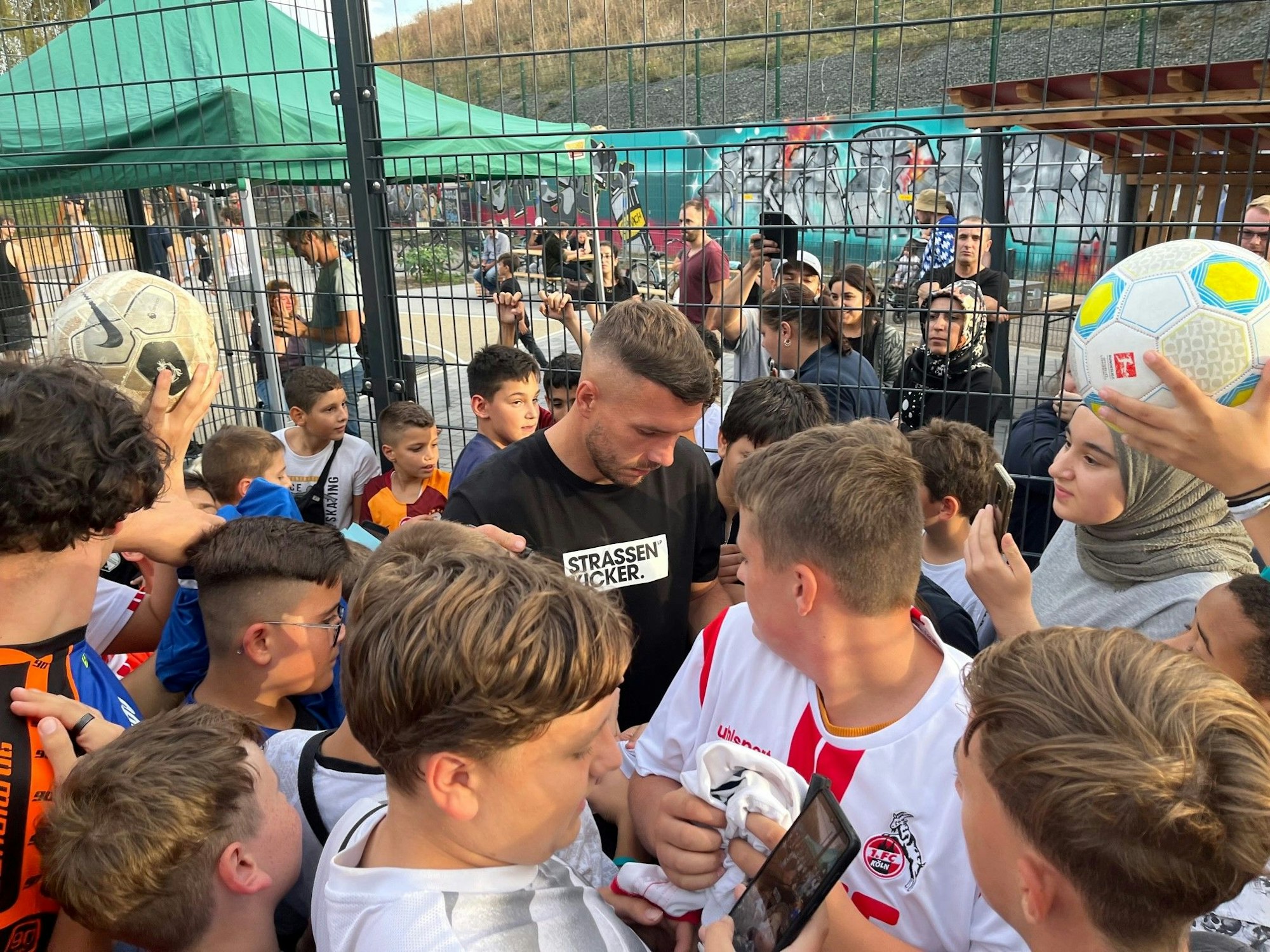 Lukas Podolski umringt von jungen Autogrammjägern.