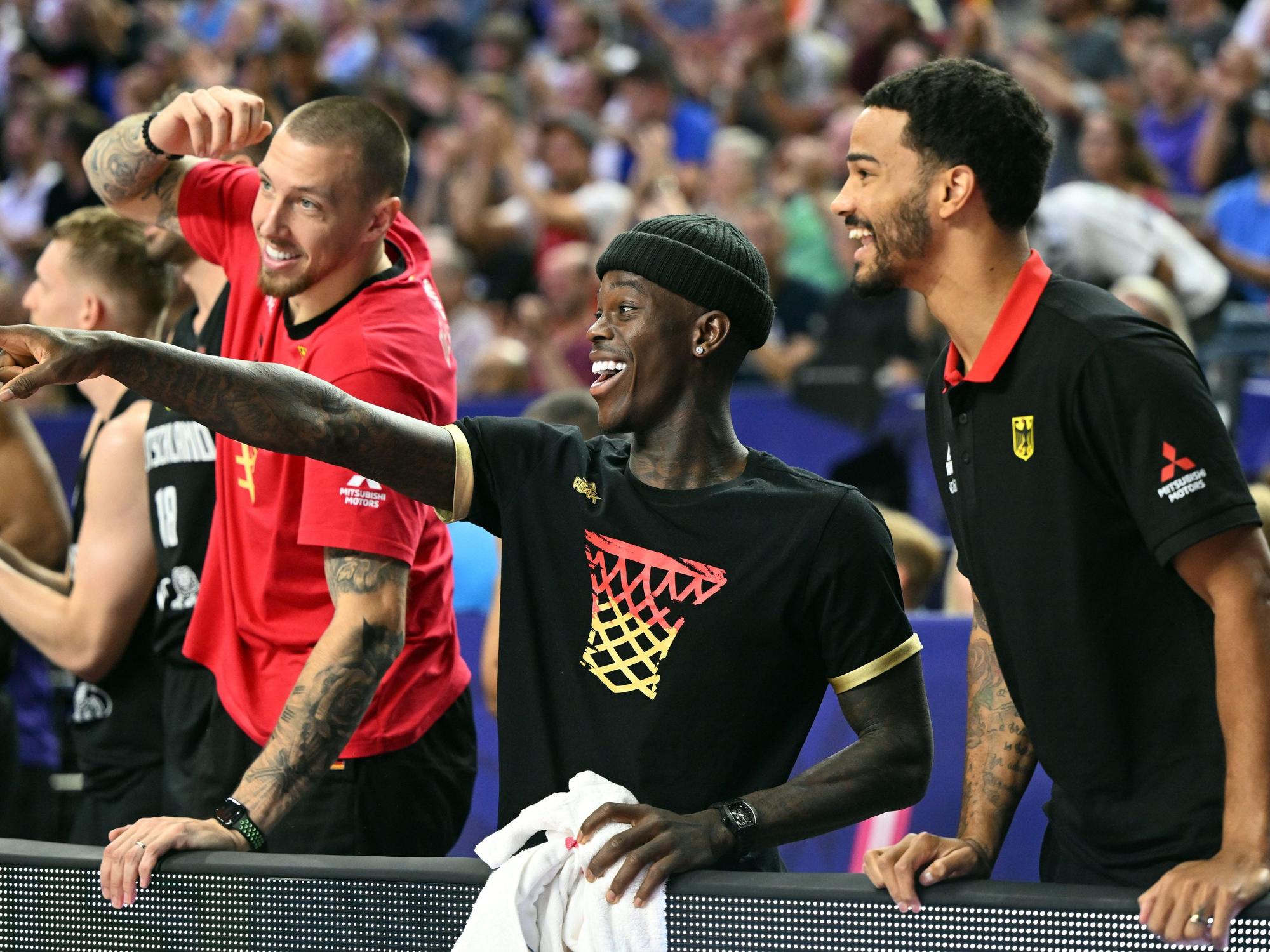 Deutschlands Daniel Theis (l.),Dennis Schröder und Nick Weiler-Babb verfolgen das Spiel auf der Bank.