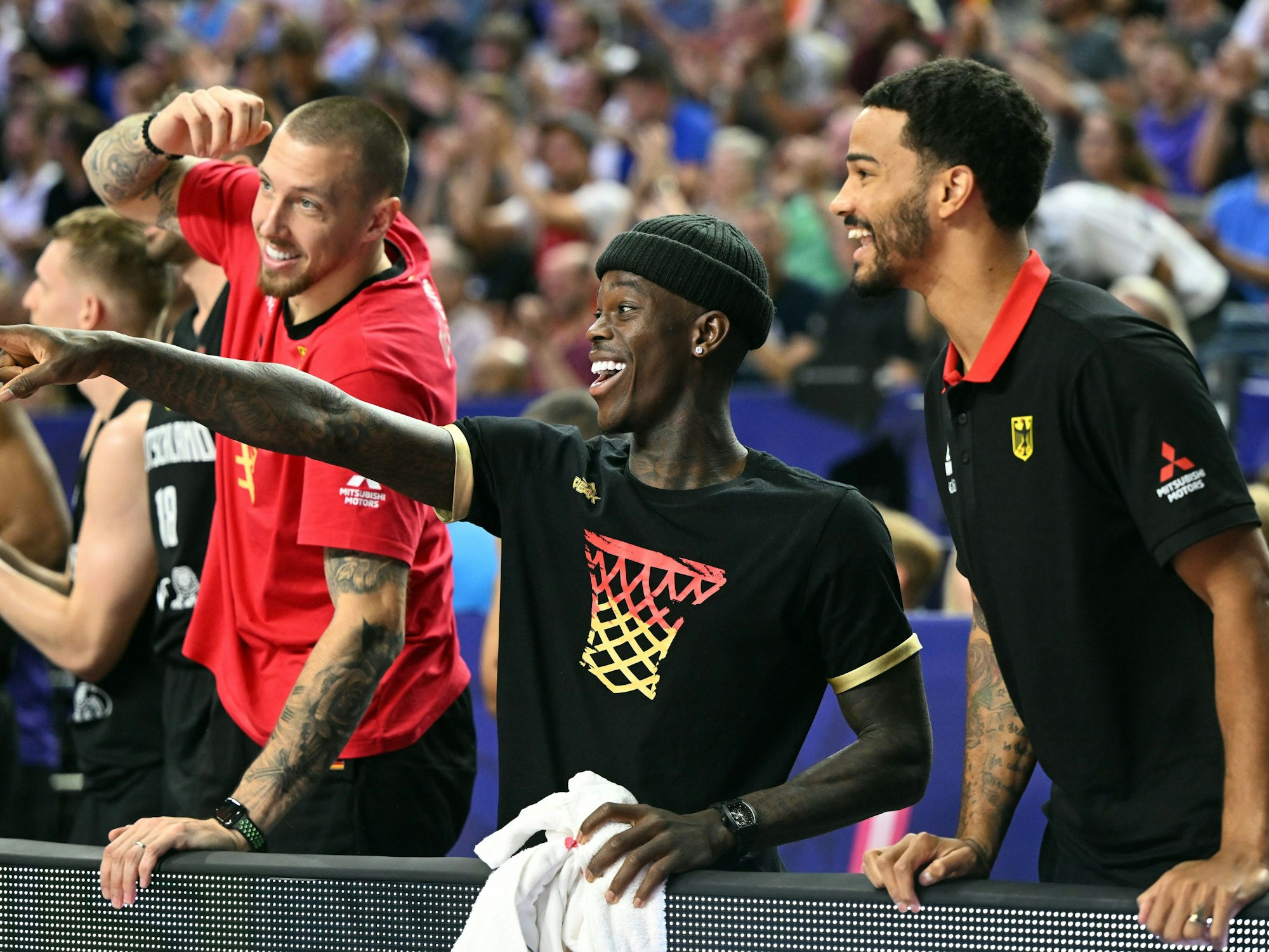 Deutschlands Daniel Theis (l.),Dennis Schröder und Nick Weiler-Babb verfolgen das Spiel auf der Bank.