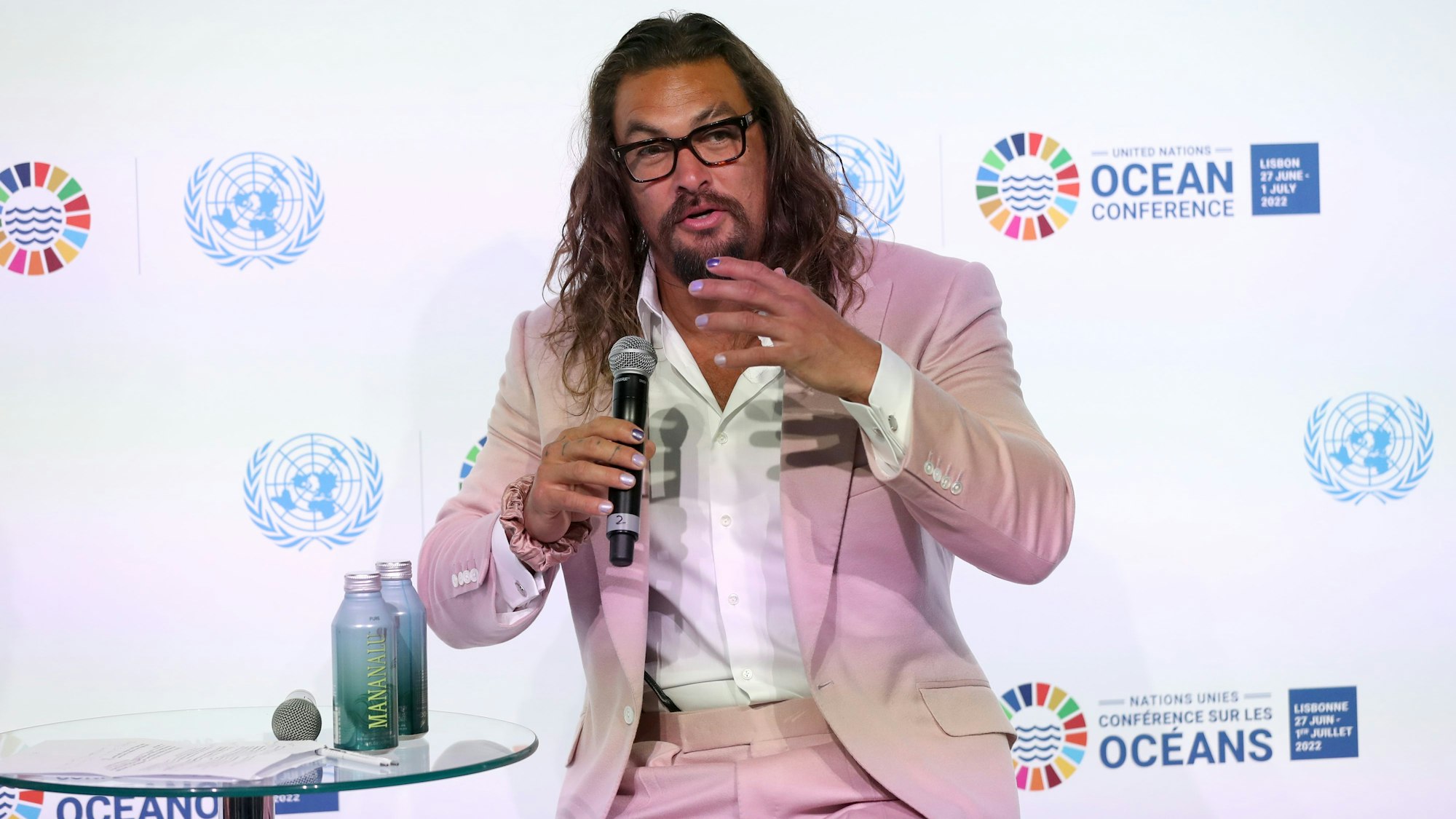 Der Schauspieler und Meeresaktivist Jason Momoa spricht auf der UN-Ozean-Konferenz im Juni 2022. Er trägt einen rosafarbenen Anzug und ein weißes Hemd.
