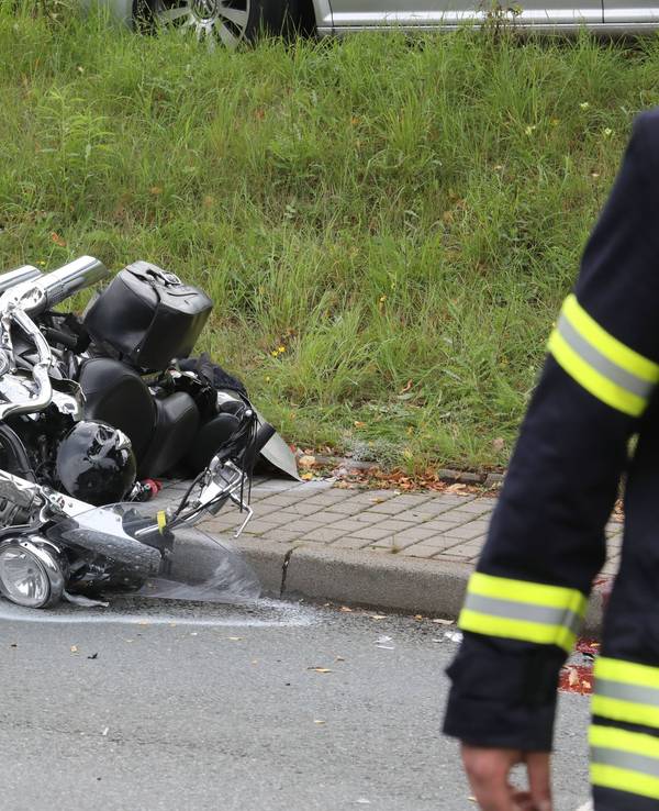 Ein verunfalltes Motorrad liegt neben einer Straße.