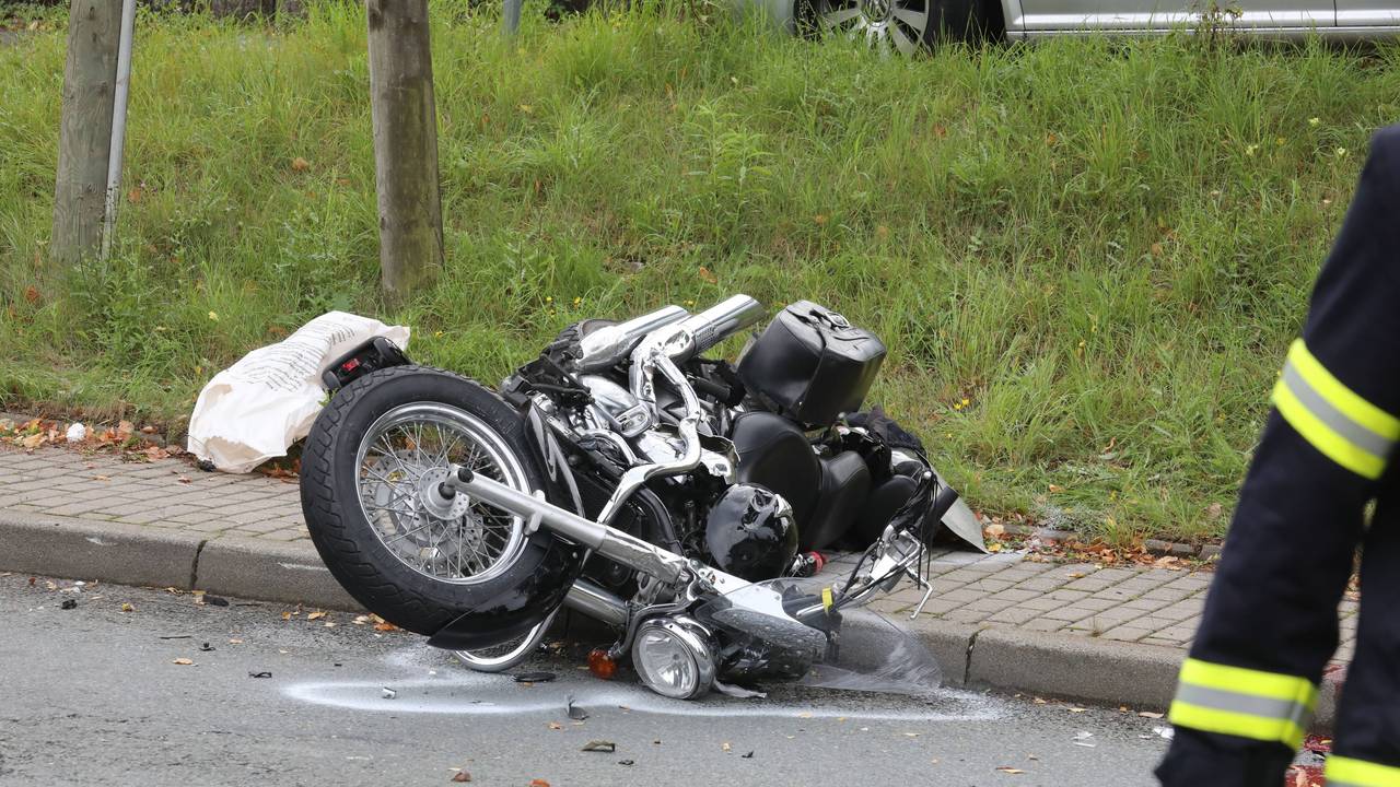 Ein verunfalltes Motorrad liegt neben einer Straße.
