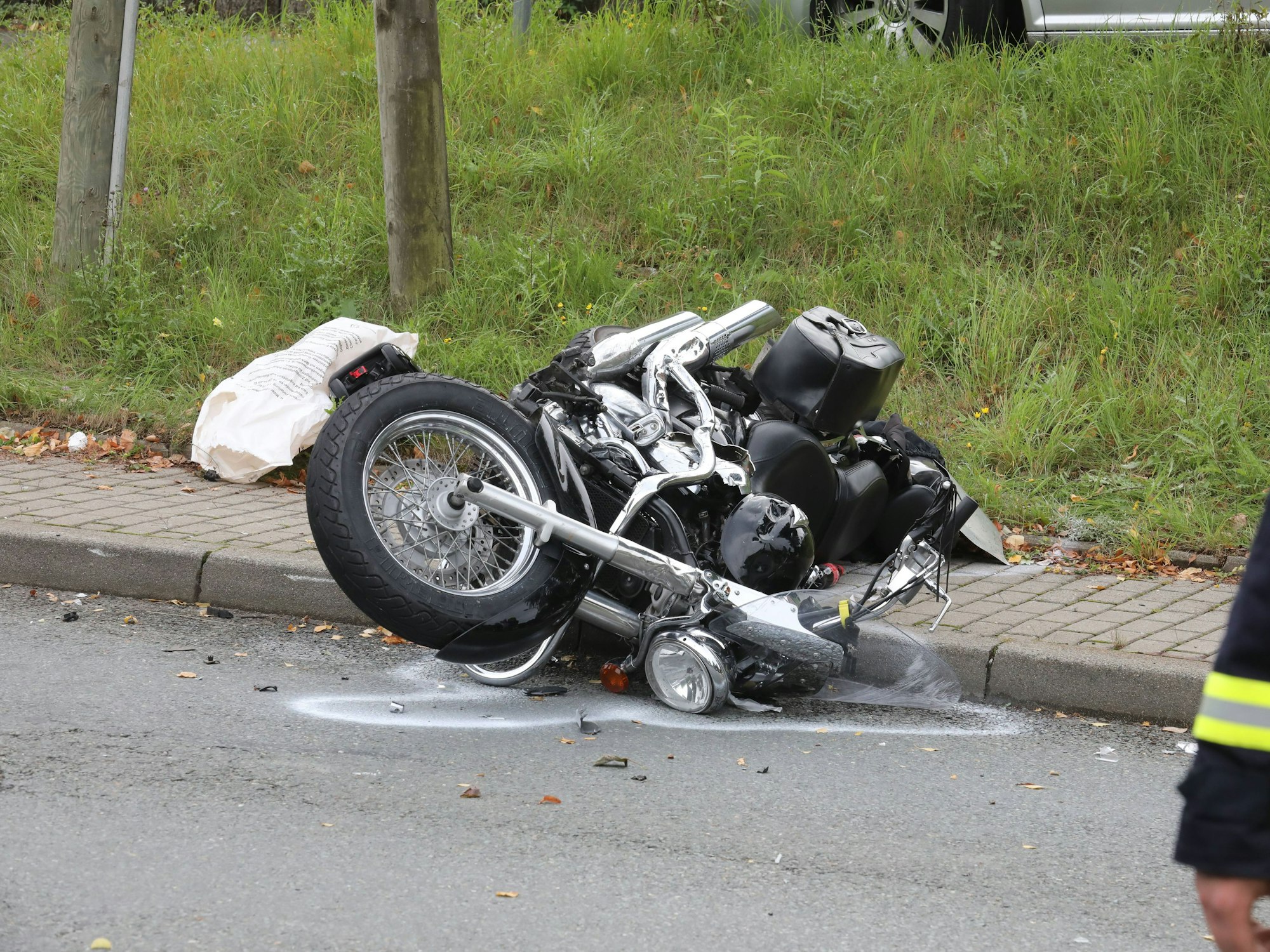 Ein verunfalltes Motorrad liegt neben einer Straße.