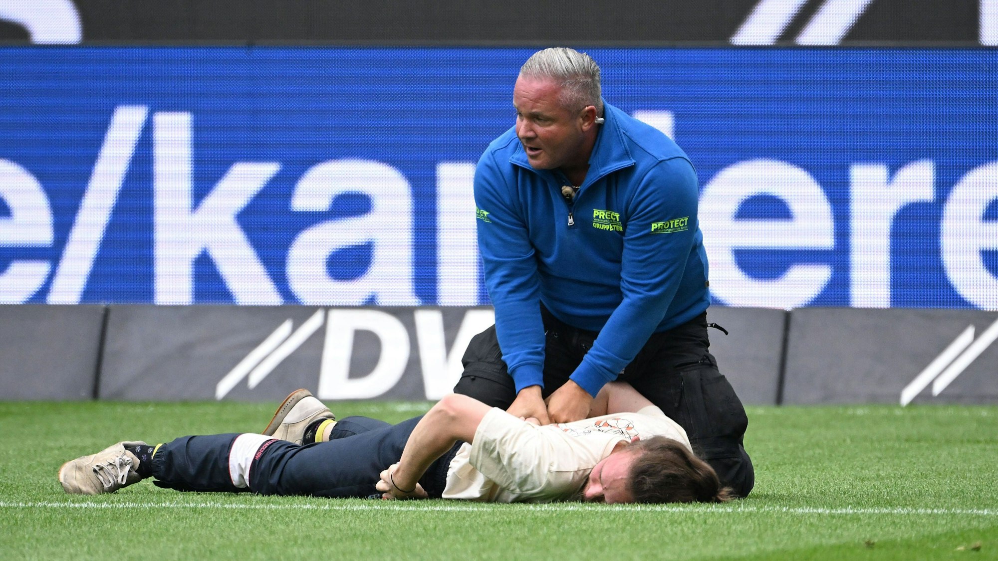 Ein Aktivist wird von einem Ordner auf dem Boden festgehalten